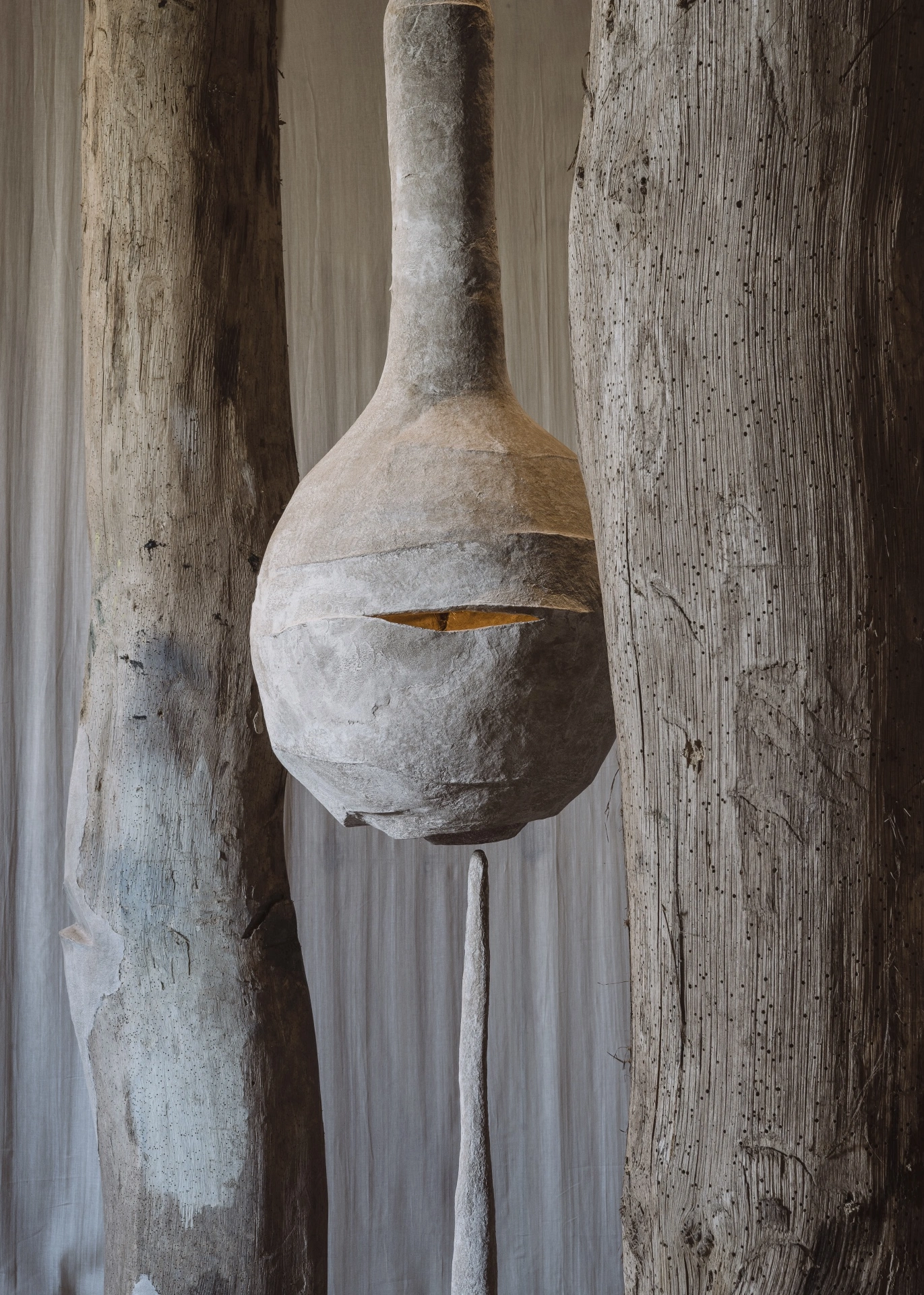remember member ember by Carolina Aguirre at THE MILL — A monolithic concrete sculpture dominates the frame, positioned centrally between two weathered timber columns.