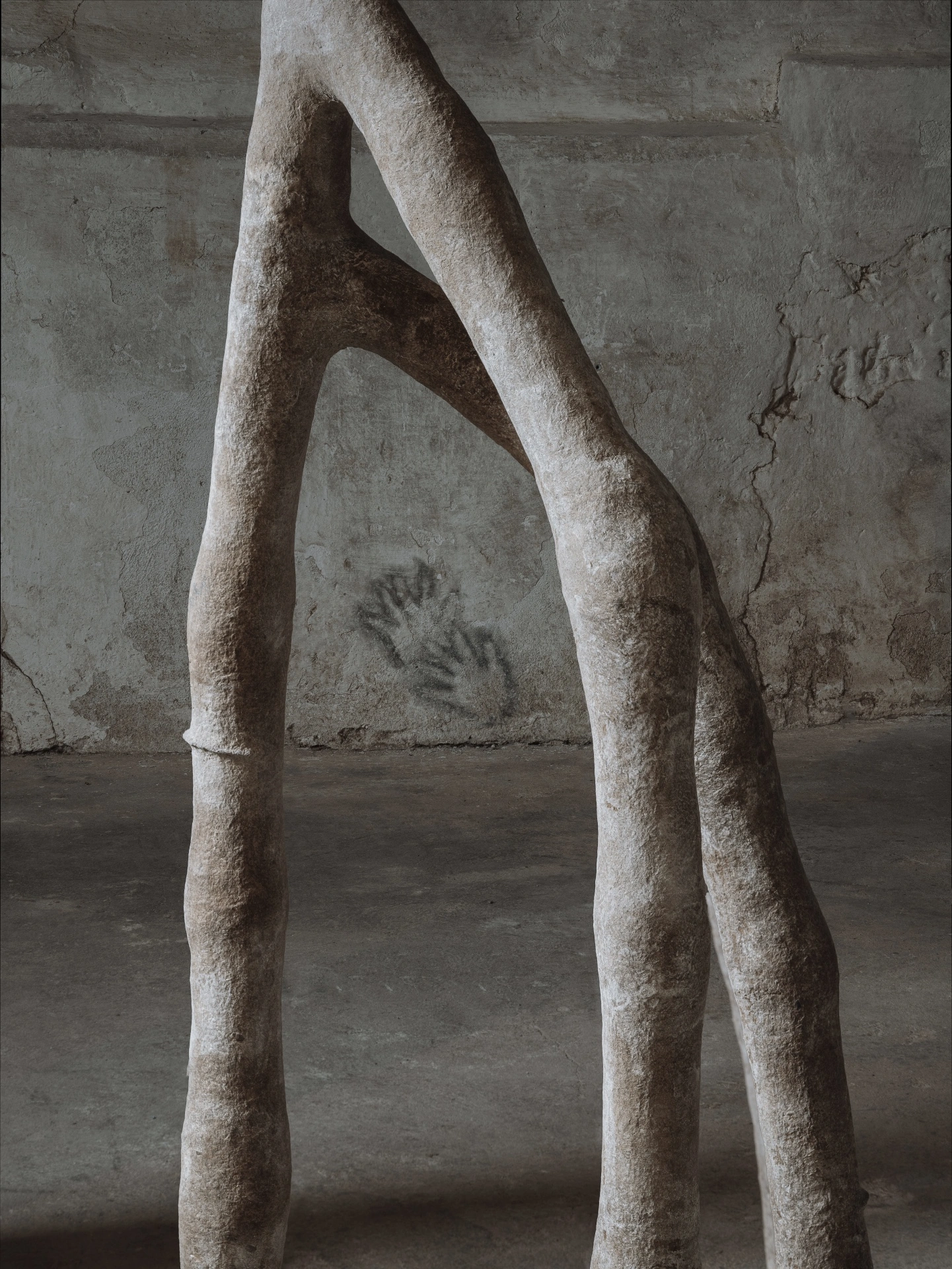 remember member ember by Carolina Aguirre at THE MILL — Three columnar concrete forms dominate the composition, their pale surfaces marked by calcified mineral deposits and weathered patina.