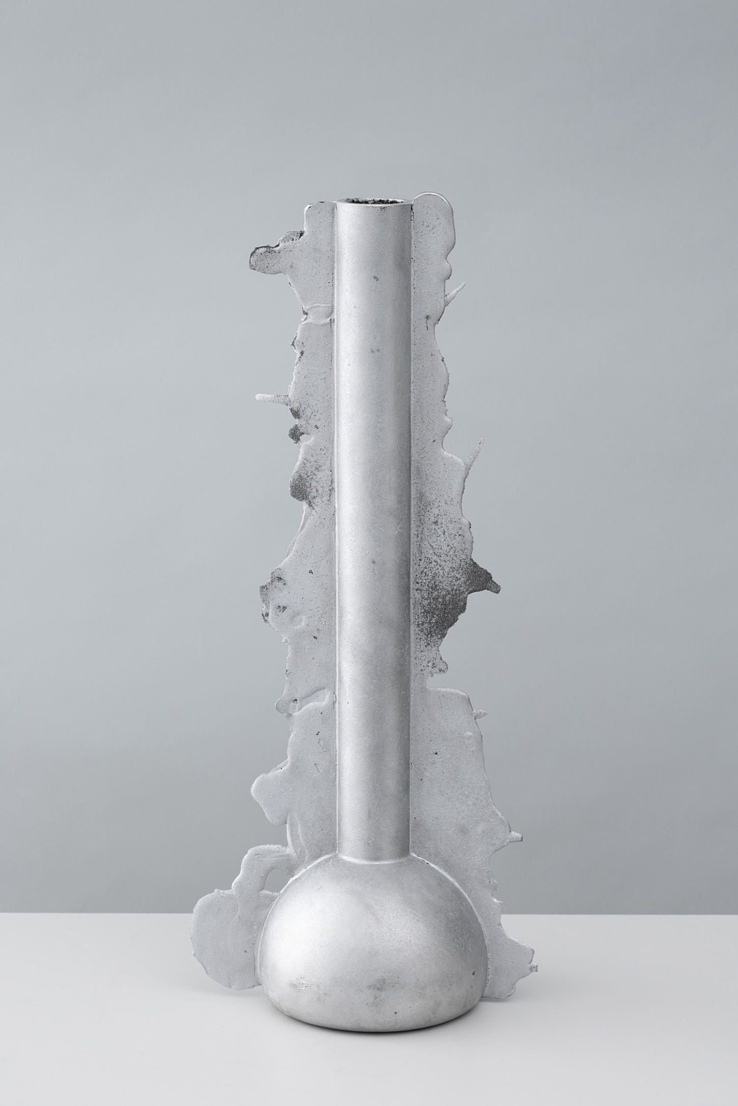 Vessels of Imperfection by Anna Zimmermann — A single cast aluminum vessel stands vertically, its cylindrical shaft rising from a bulbous, spherical base.