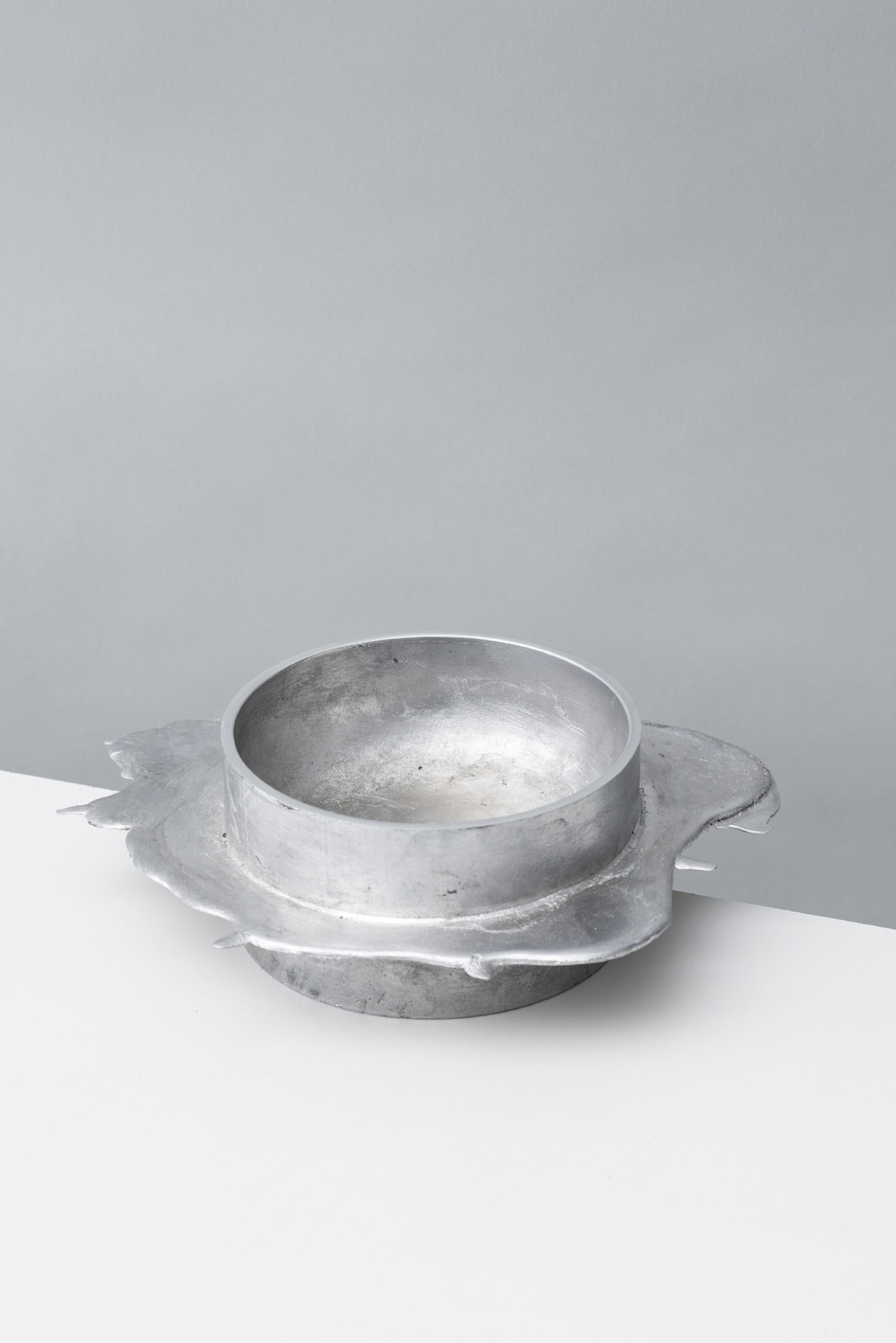 Vessels of Imperfection by Anna Zimmermann — A single aluminum casting vessel positioned frontally against a divided gray-white ground.