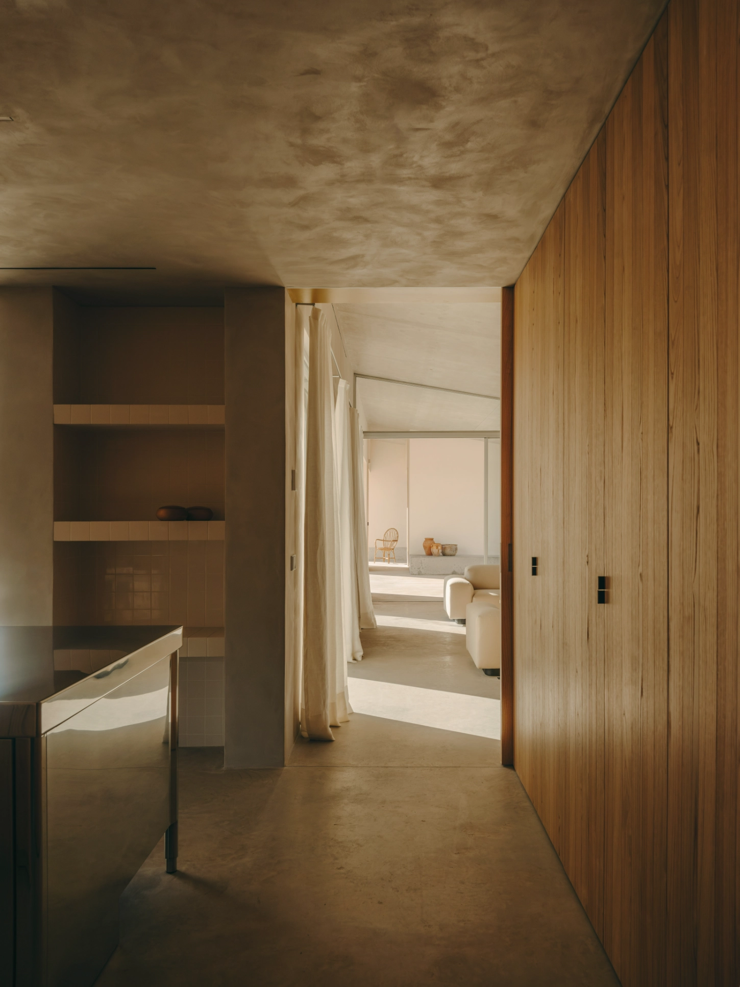 Casa TD by Skye Maunsell, Jordi Veciana and Juan Gurrea Rumeu — A corridor lined with timber-clad walls frames a succession of spatial thresholds, anchored by a polished concrete floor that extends seamlessly to the...