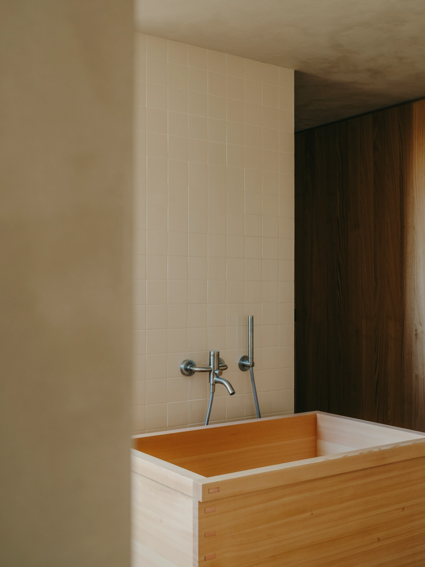 Casa TD by Skye Maunsell, Jordi Veciana and Juan Gurrea Rumeu — A Japanese-inspired wooden soaking tub occupies the foreground, its timber exterior stained in warm honey tones with a white interior rim.