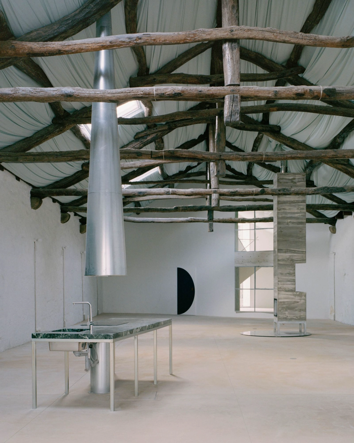 'House with many faces' by Fala Atelier — A converted industrial space reveals its structural bones beneath a corrugated metal roof supported by weathered timber beams.