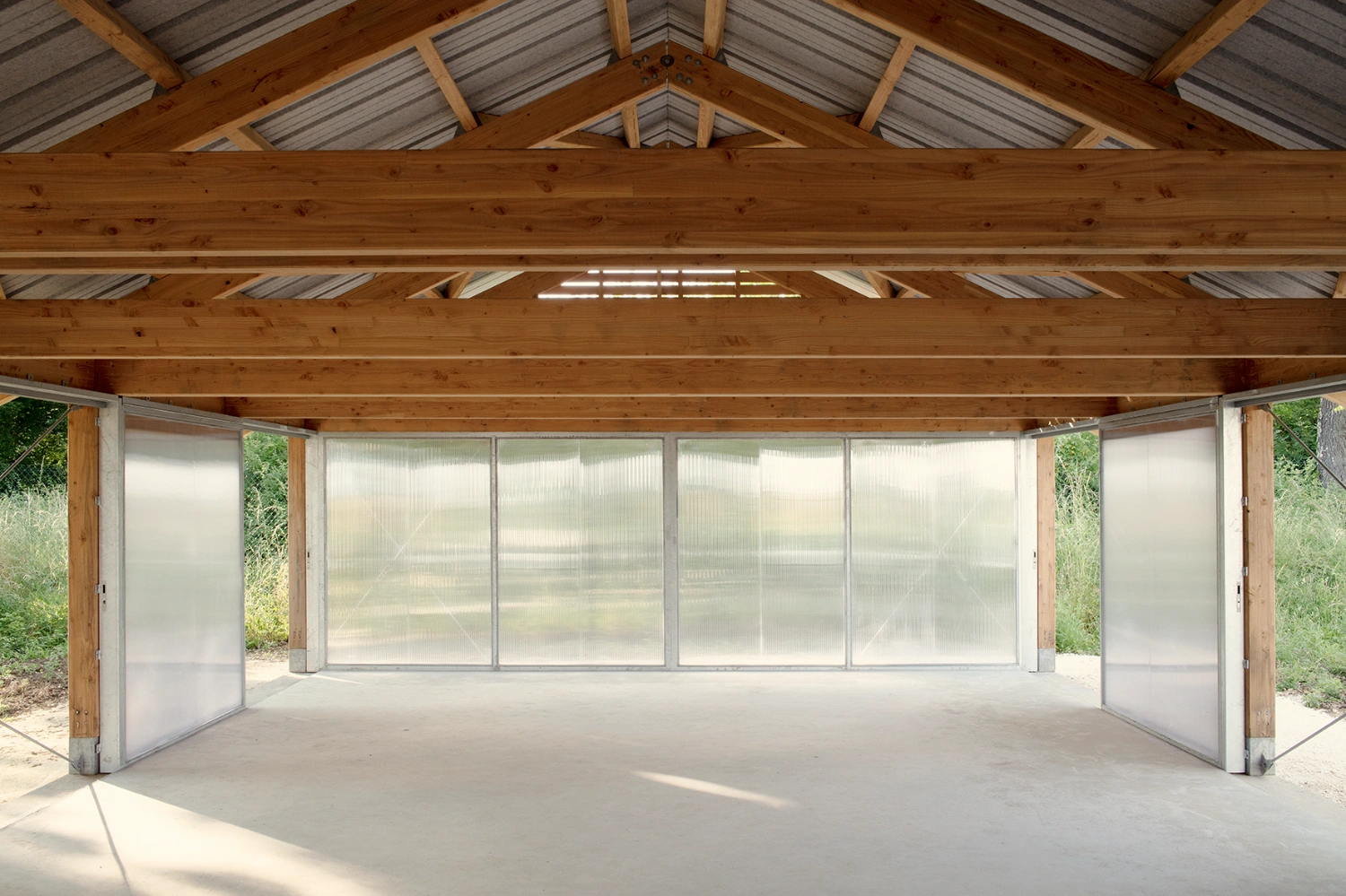 Garden Pavilion by Esnard Sanz Architectes — A timber-framed garden pavilion photographed from the interior, revealing the structural clarity of its post-and-beam construction.