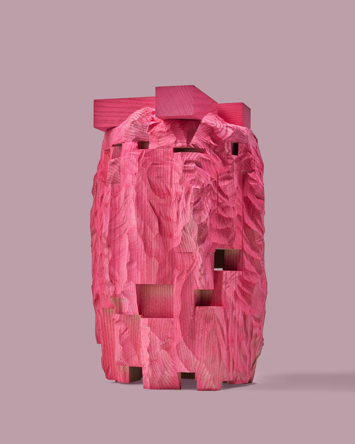 PINKDOM by Knit Pigment — A carved wooden sculpture anthropomorphizes architectural form through a monolithic pink block featuring a simplified face with two rectangular eye voids...