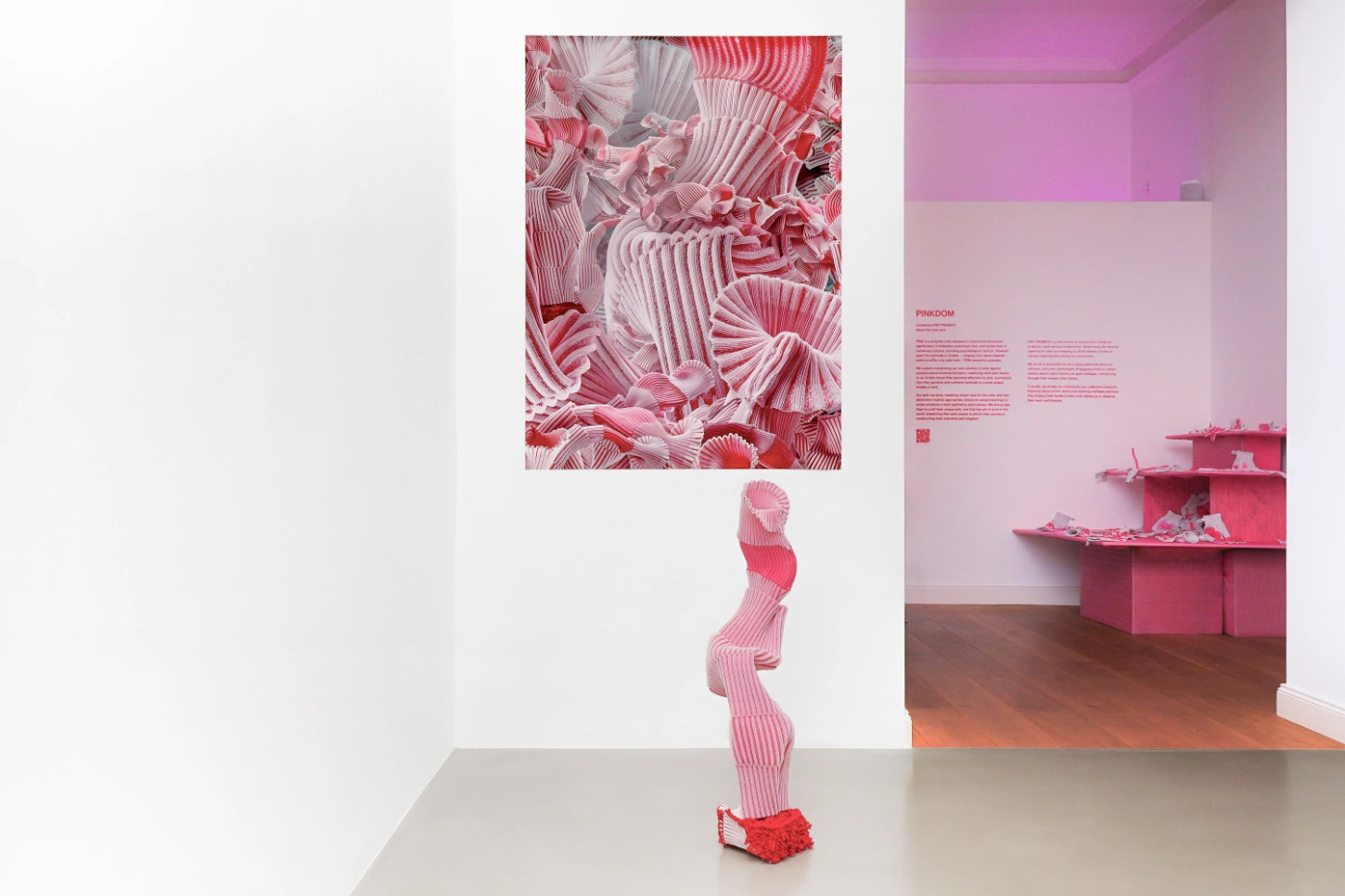 PINKDOM by Knit Pigment — A monochromatic hot-pink sculptural form dominates the gallery floor, constructed from ribbed material with an anthropomorphic presence.