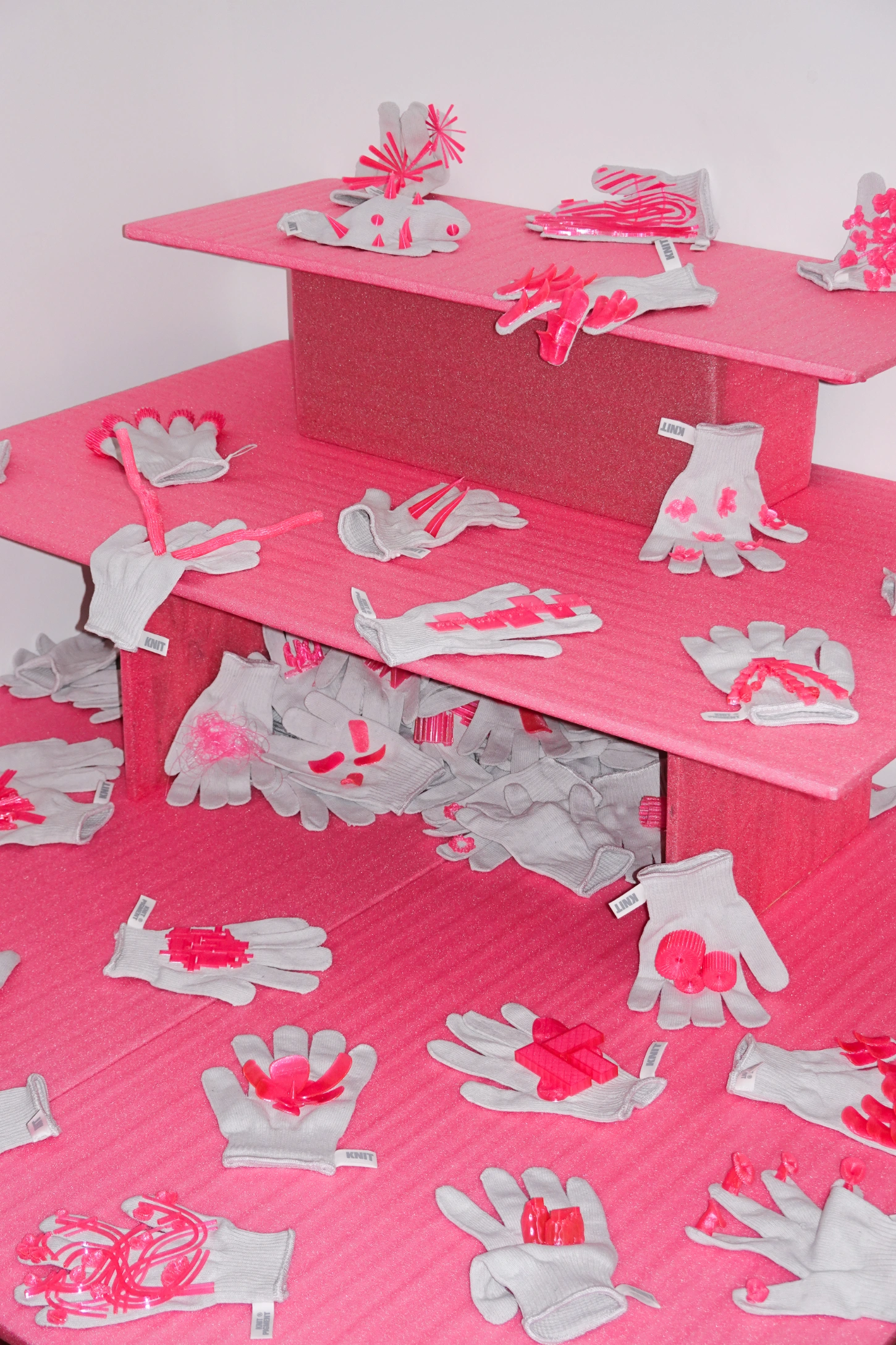 PINKDOM by Knit Pigment — PINKDOM installation view featuring hand-knitted textile sculptures arranged across tiered pink plywood display platforms.