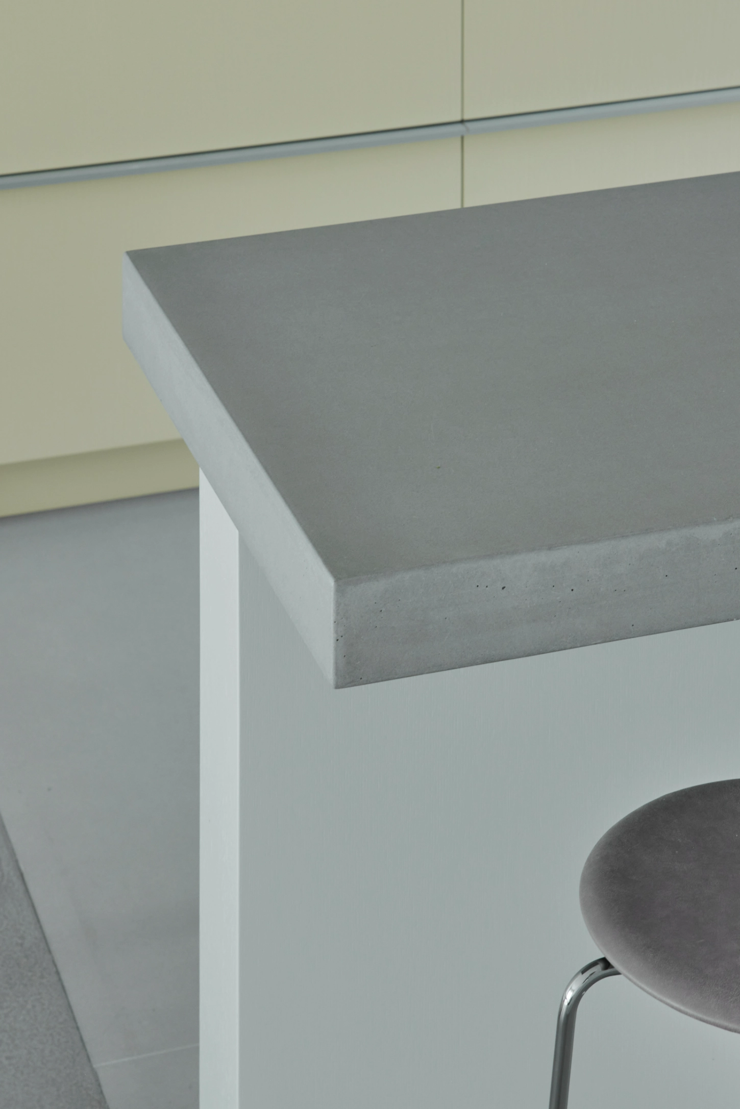 VVV by i.B Archstudio — Close-up detail of a cantilevered concrete shelf with finished edge, supported by a white modular furniture unit that functions as a subtle room divider.