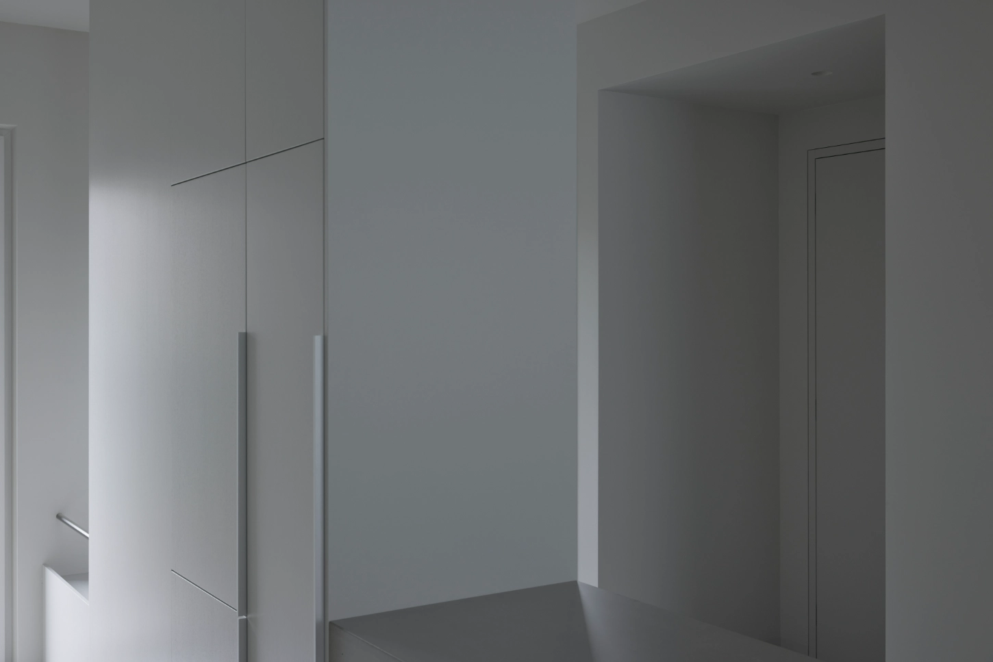 VVV by i.B Archstudio — A corridor defined by clean geometric planes: white plaster walls rise uninterrupted to a ceiling plane, while a darker flooring material grounds the space.