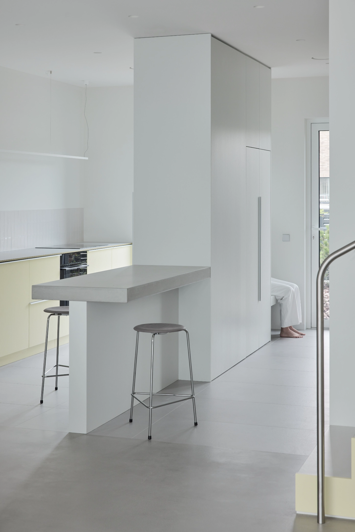 VVV by i.B Archstudio — A minimalist kitchen interior centered on a monolithic concrete island with cantilevered seating.