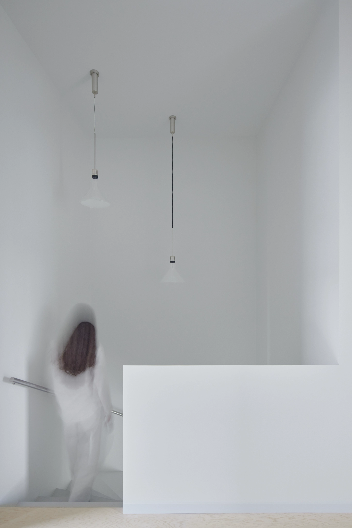 VVV by i.B Archstudio — A figure in white clothing stands before a cream-colored modular furniture unit that functions as a spatial divider within the open-plan interior.