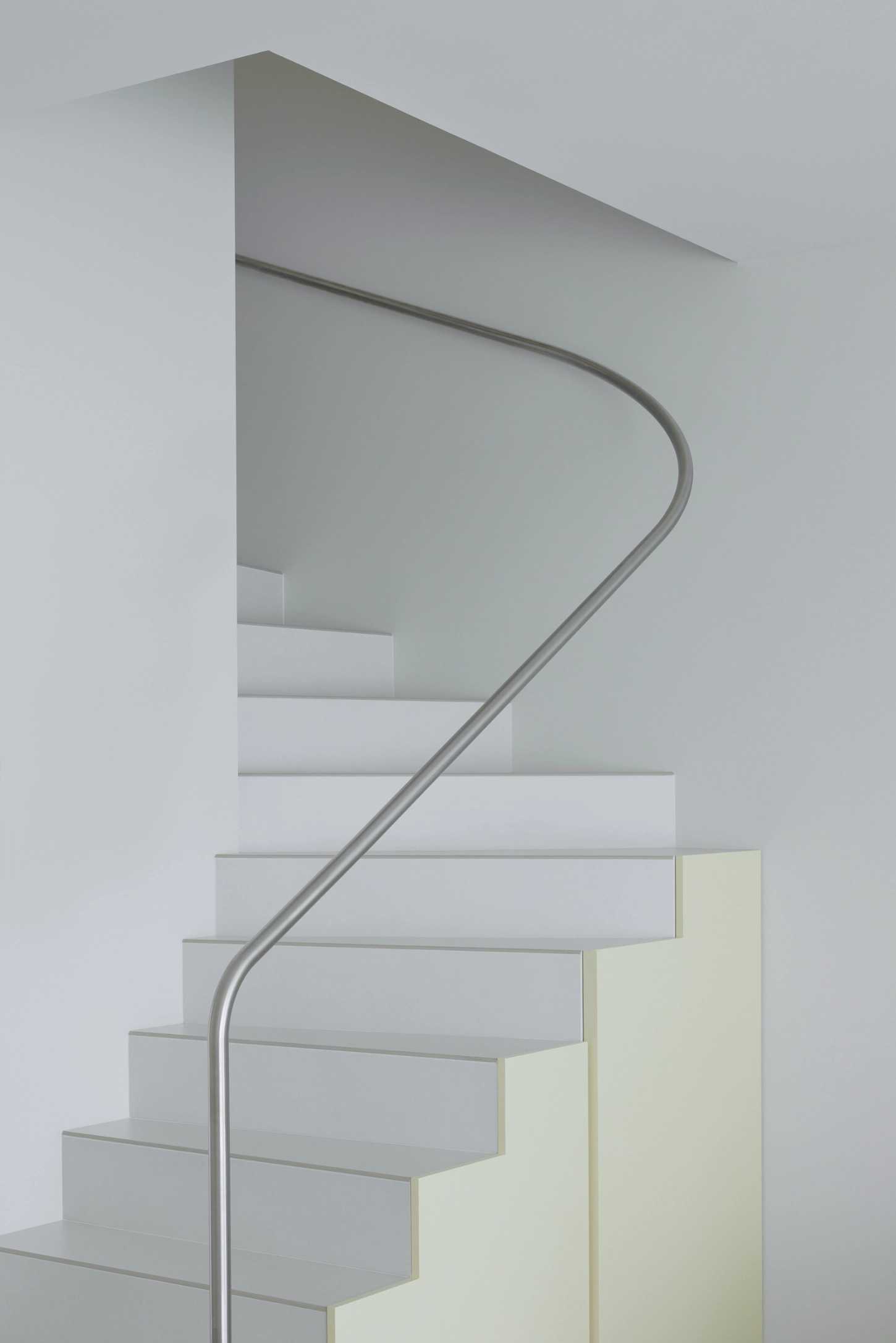 VVV by i.B Archstudio — A sculptural staircase descends through white interior space, its concrete treads stacked with sharp horizontal edges that create rhythmic shadow lines...