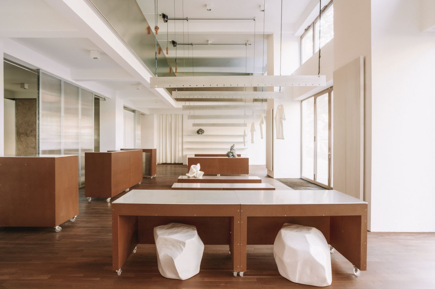 KMB Torstrasse 140 by Vaust — A reconfigurable workspace interior defined by mobile timber-framed carts with white laminate tops positioned along a central axis, their oiled wood sides...