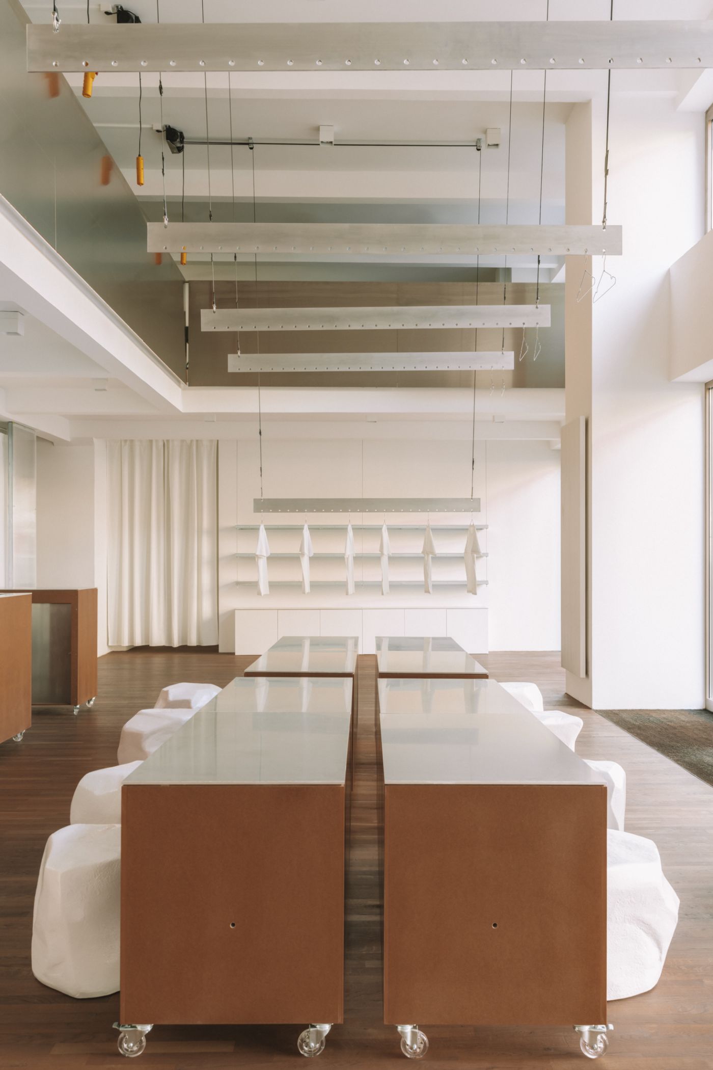 KMB Torstrasse 140 by Vaust — A symmetrical interior workspace centered on two mobile timber carts with oiled wood sides and white laminate tops, positioned on casters along a linear axis.