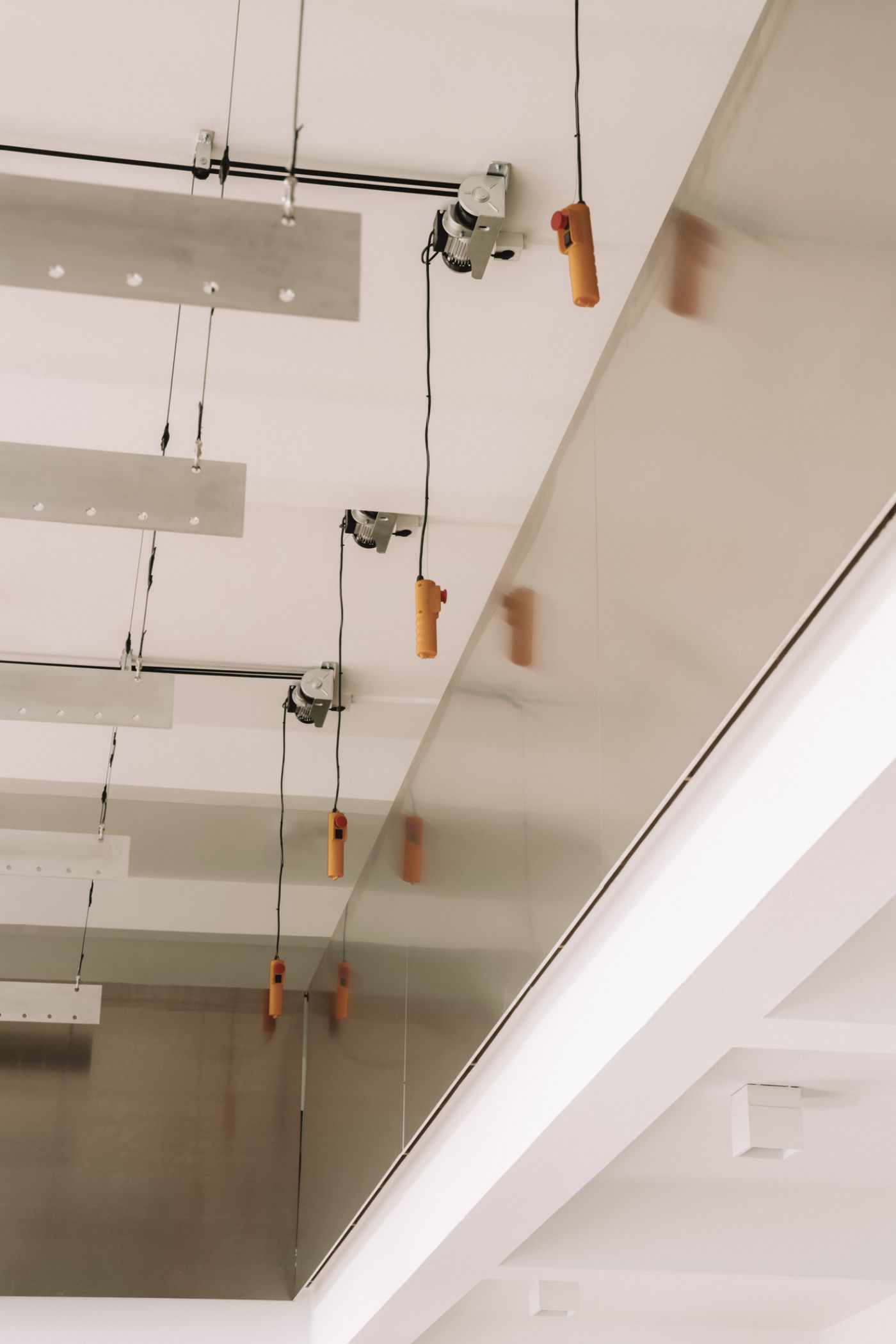KMB Torstrasse 140 by Vaust — Overhead view of a ceiling-mounted display and storage system featuring suspended aluminum rails at staggered heights with mechanical pulleys and...