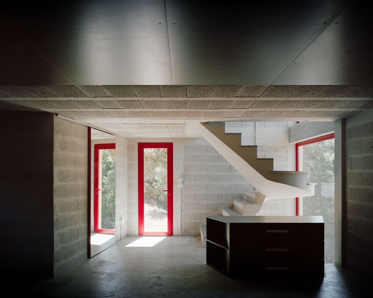 House in Ancede by atelier local — The ground floor interior reveals a concrete masonry construction with exposed mortar joints and raw concrete flooring.