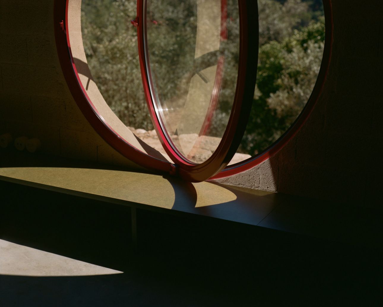 House in Ancede by atelier local — A threshold moment captured through a circular red-framed opening, revealing layered spatial depths.