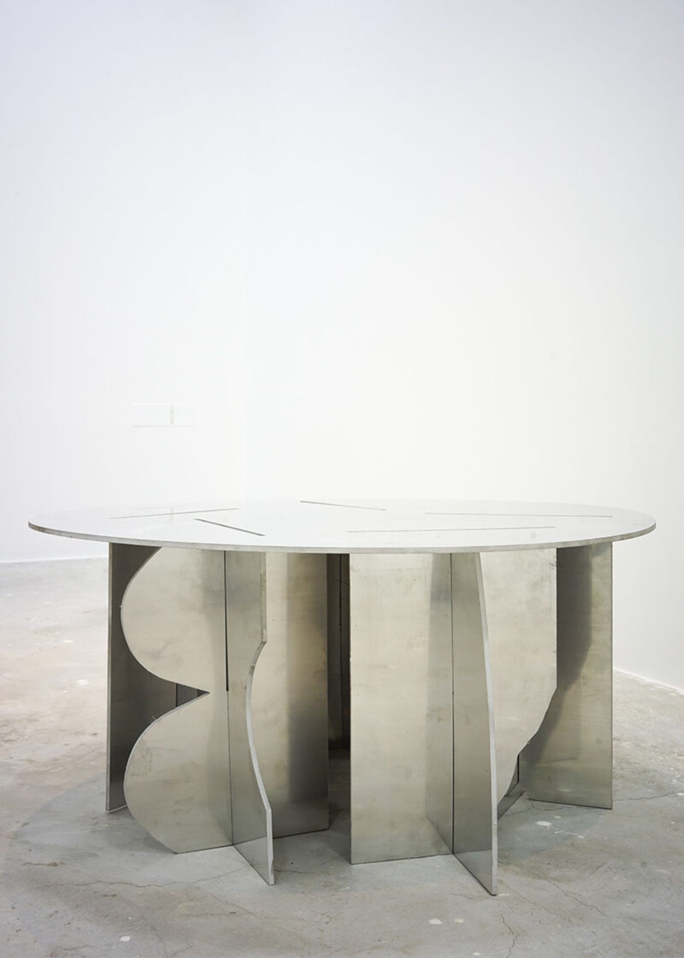Selected Works by Bahraini-Danish — A circular dining table with an undulating tabletop supported by sculptural concrete or cast stone pedestals.