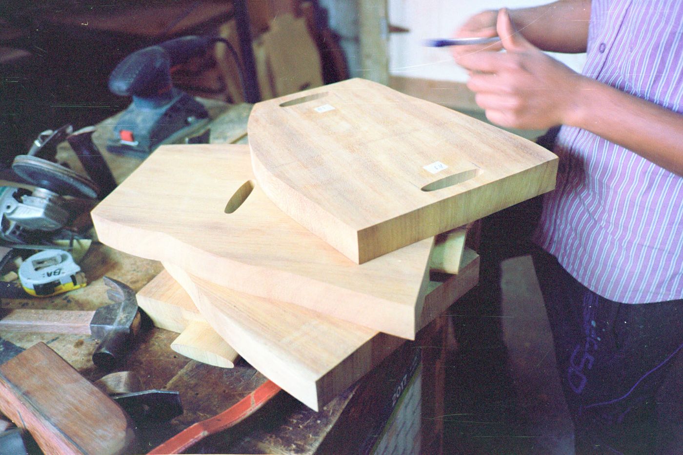 Selected Works by Bahraini-Danish — A wooden table in progress occupies the workshop surface, its design vocabulary evident in the stacked components.