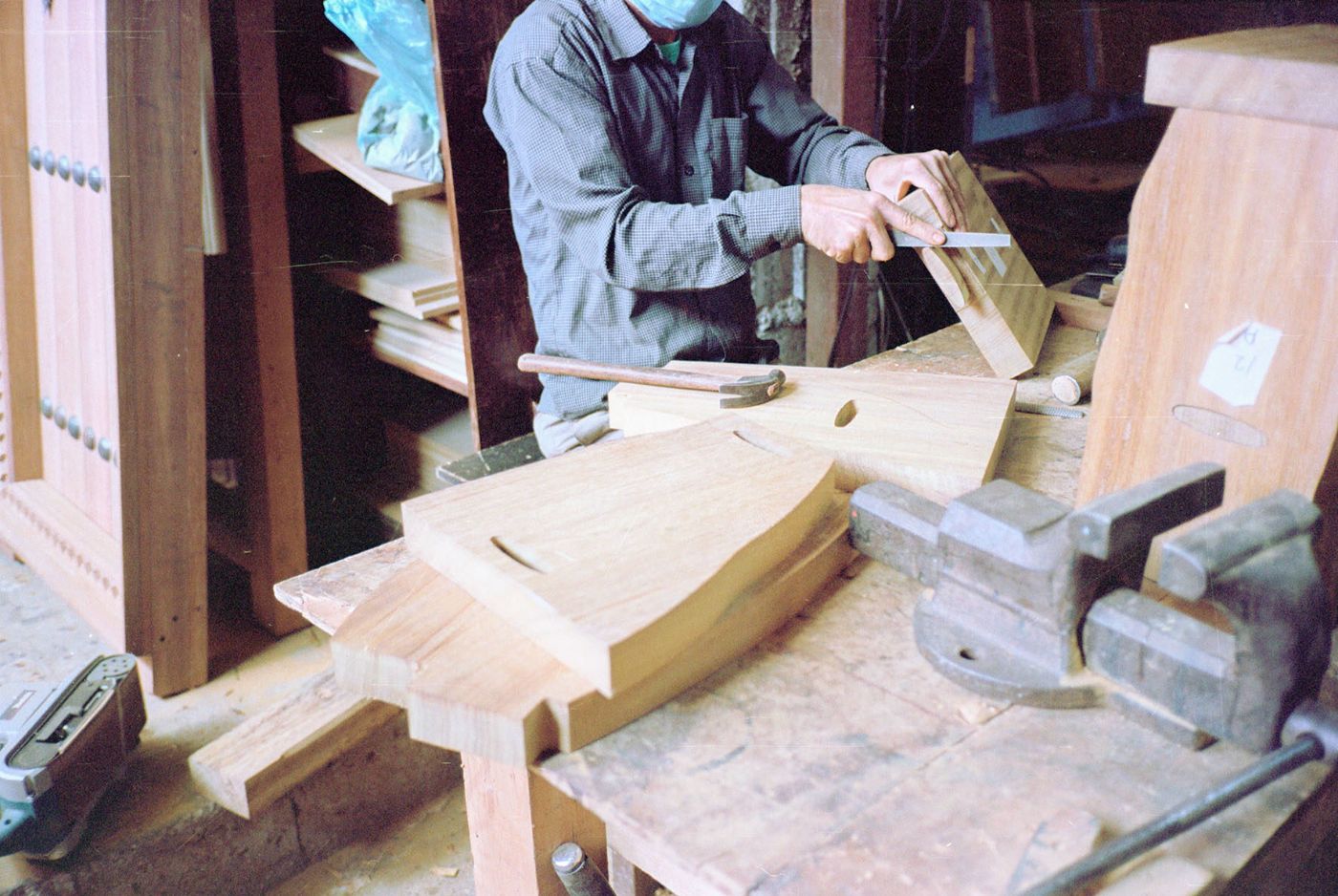 Selected Works by Bahraini-Danish — A craftsperson works on a wooden table in progress, demonstrating hand-finishing techniques on walnut or similar dark hardwood.