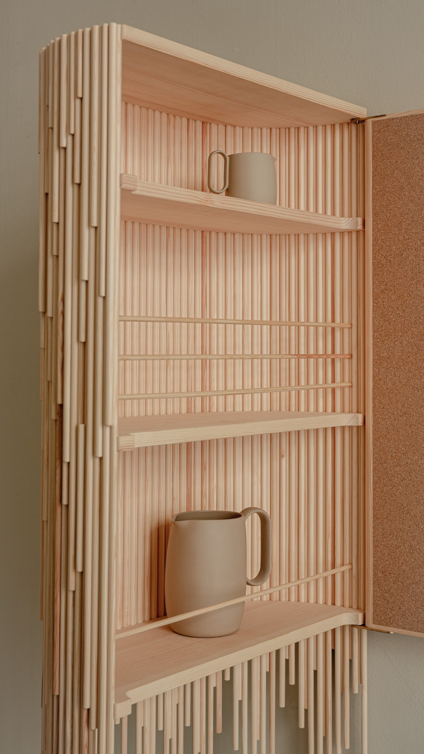 TRACES Exhibition by Antrei Hartikainen — Open wooden cabinet with pine slat construction throughout, featuring vertical elements of graduated lengths suspended from a horizontal rail to create a...