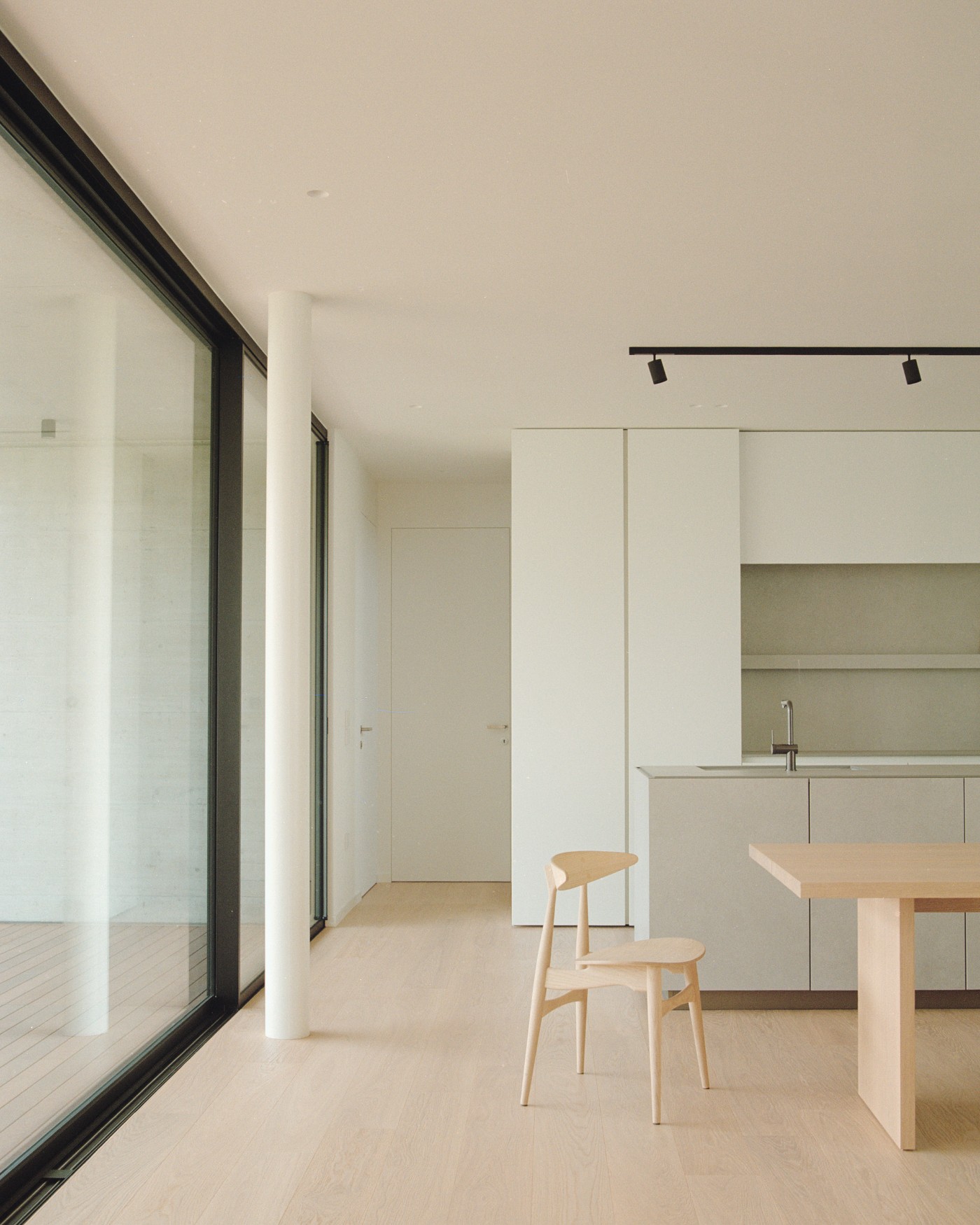 House NF by Didonè Comacchio Architects — The kitchen and dining area of House NF presents a minimalist interior defined by rectilinear forms and a restrained material palette.