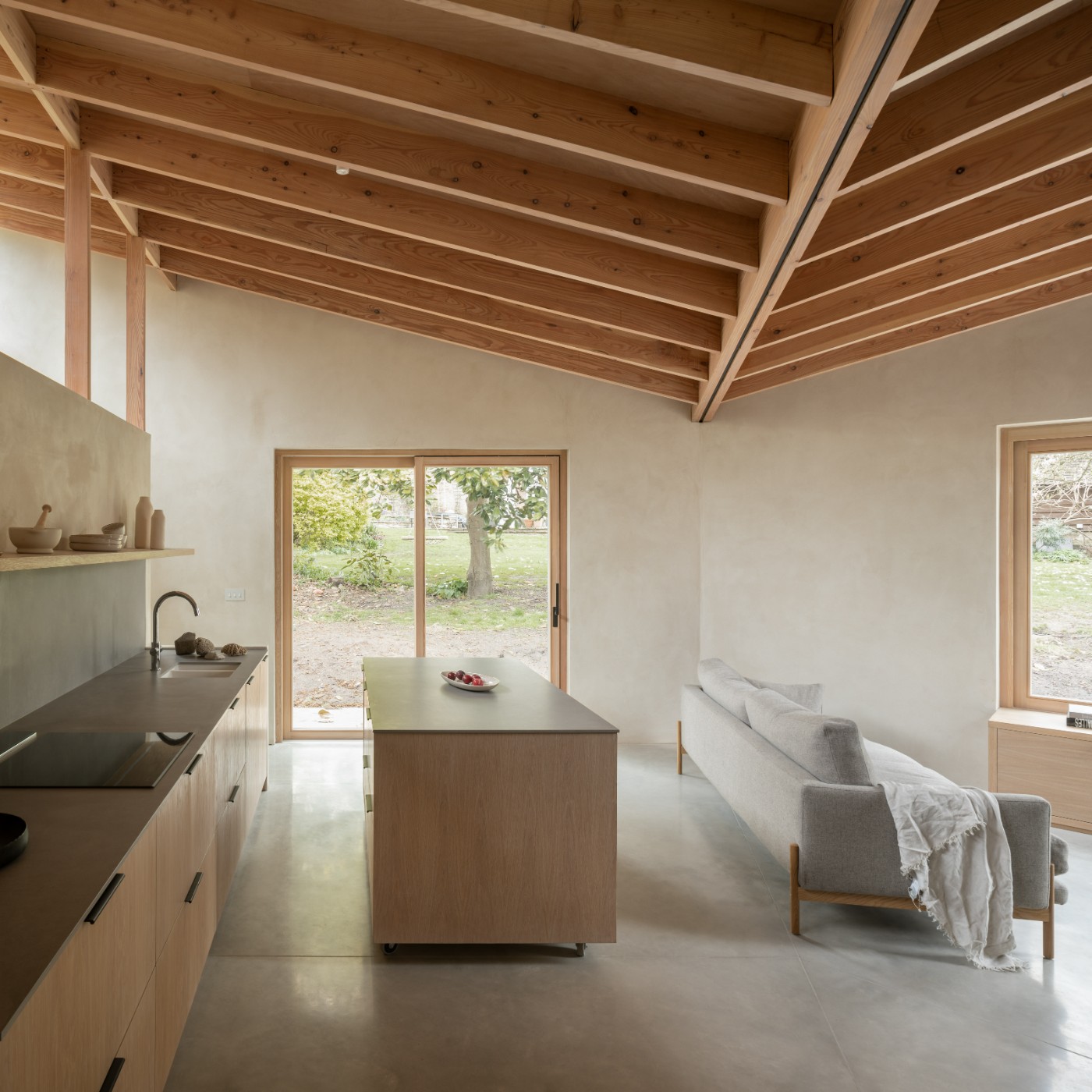 Butterfly House by Oliver Leech Architects — Interior view of the open-plan kitchen and living area within the Butterfly House, showcasing the fanned pitch timber structure overhead.