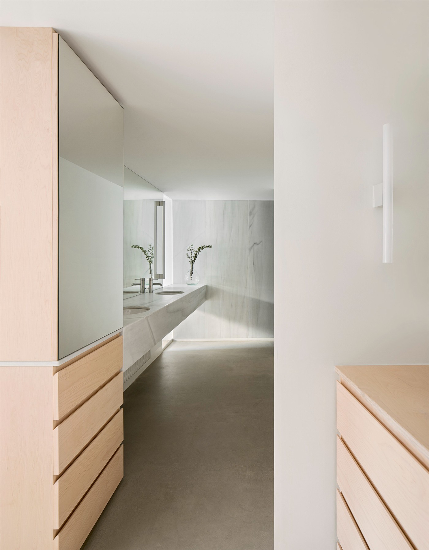 Red House by Aramé Studio — A narrow bathroom corridor lined with light oak cabinetry featuring horizontal drawer divisions running the full length of the left wall.