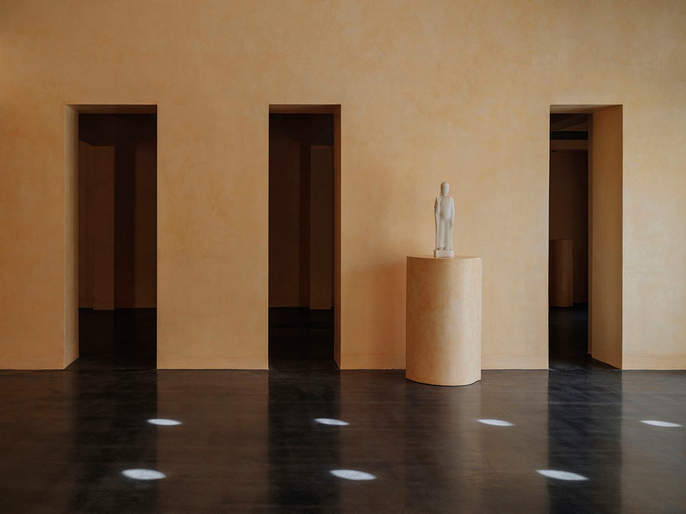 'The Field' by TEAM_BLDG by TEAM BLDG — A rendered interior space with warm sandalwood-yellow walls frames three deep rectangular voids receding into shadow.
