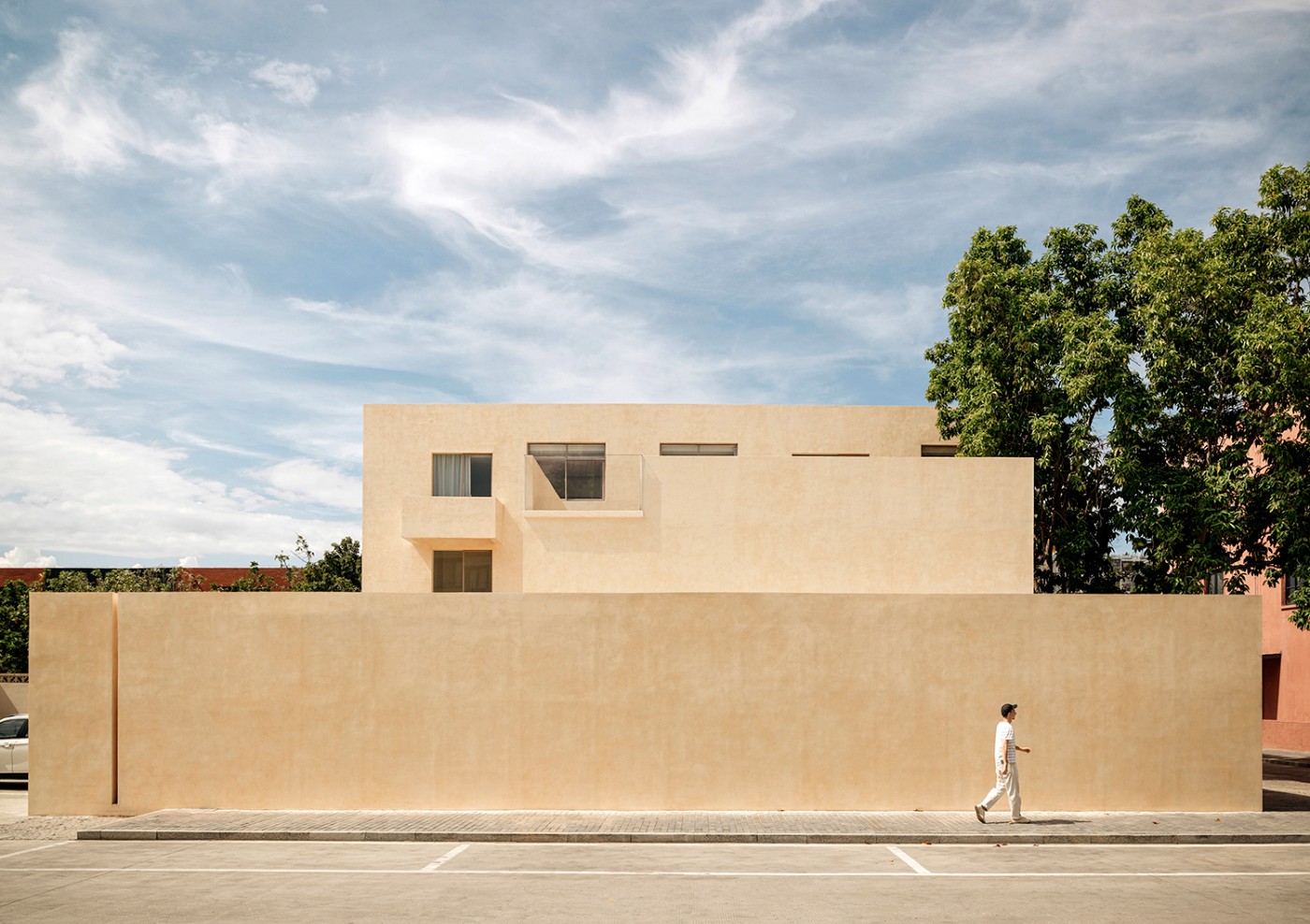 'The Field' by TEAM_BLDG by TEAM BLDG — A rendered facade in warm sandalwood-yellow tones fronts the renovated studio, its monolithic surface punctuated by a single horizontal aperture.