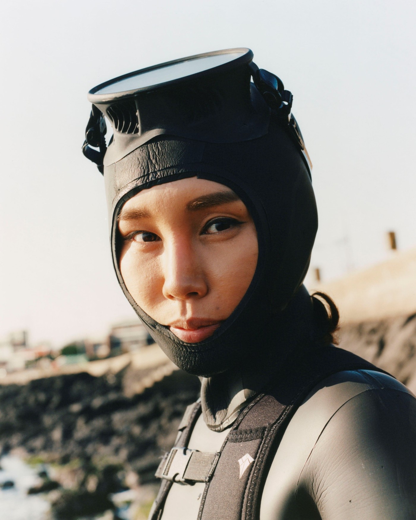 'The Last Mermaid' by Peter Ash Lee — A close-up portrait of a Haenyo diver positioned against a hazy coastal landscape.