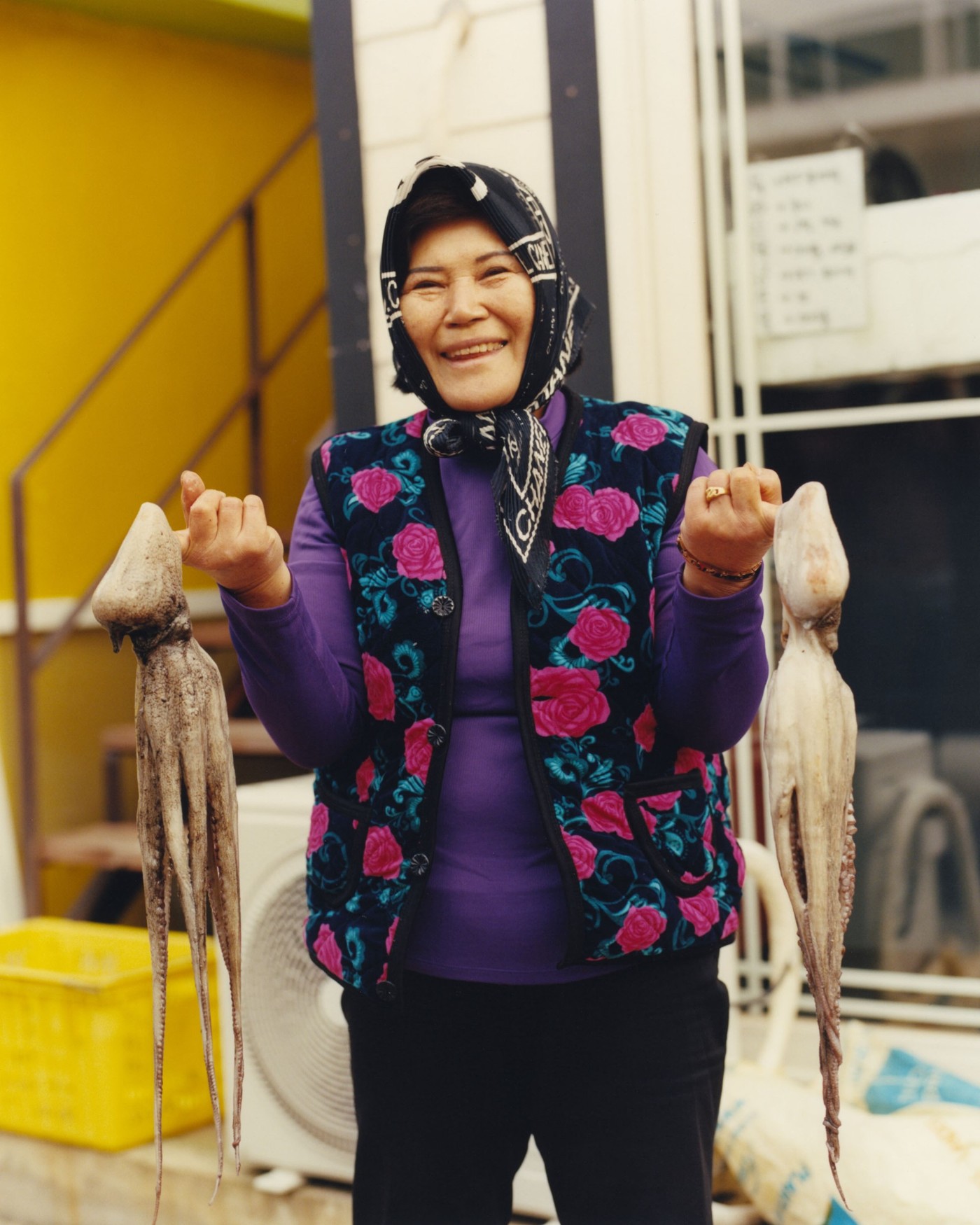 'The Last Mermaid' by Peter Ash Lee — A Haenyo diver displays her catch of squid against an industrial interior backdrop.