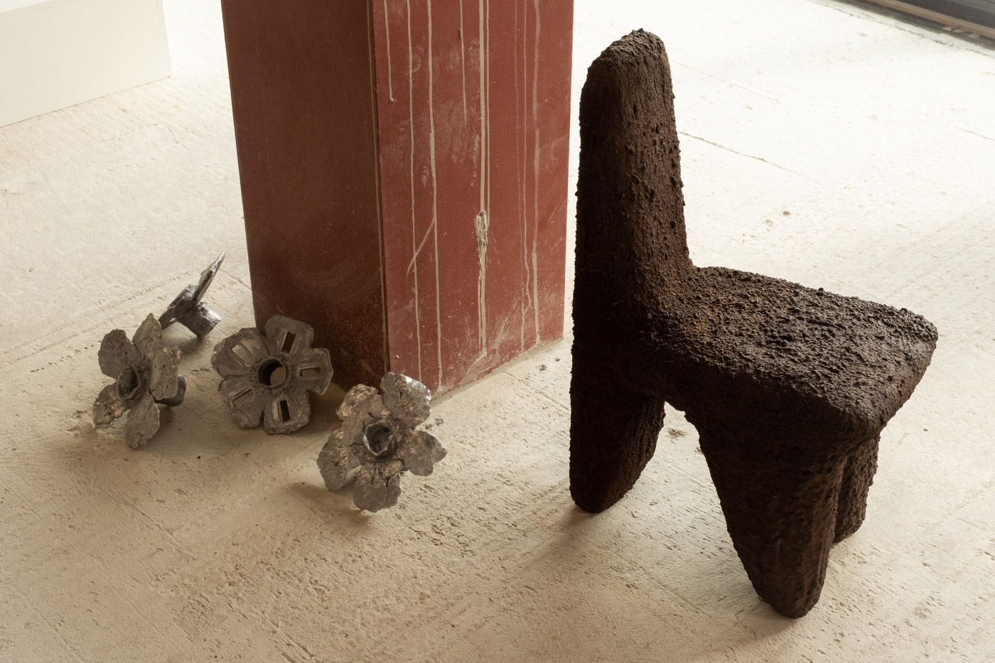 Forma - Nomad Gallery in Berlin by Forma Gallery — Sculptural forms in dark rammed-earth or concrete dominate the foreground of this gallery installation view.