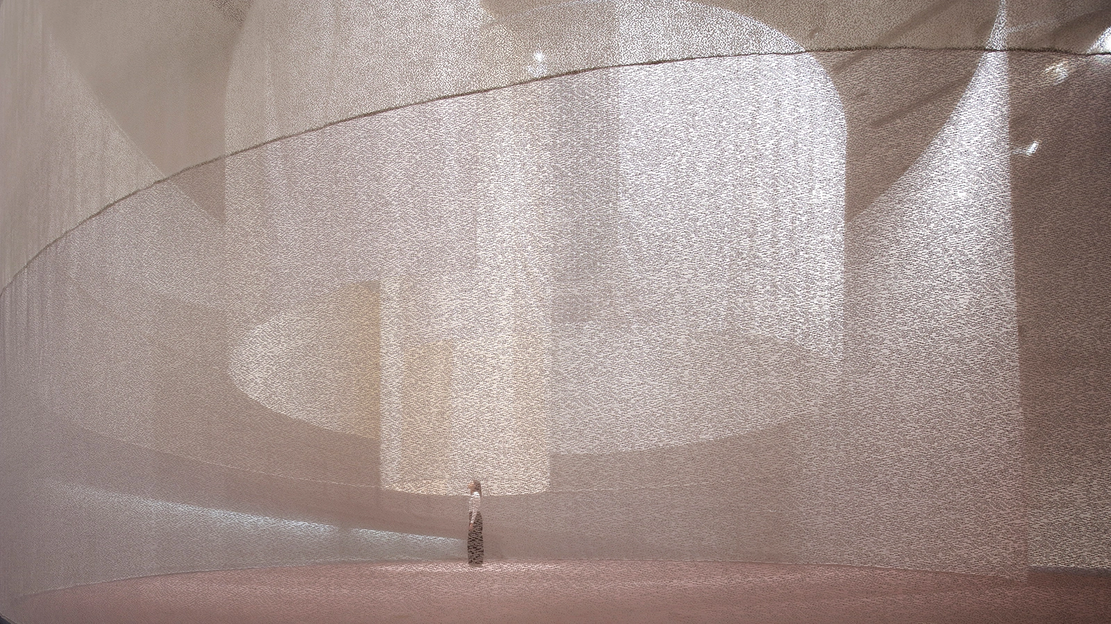Three Tones at Spiral Garden by Isaku Design + Tashiro Design — Within a cylindrical exhibition space, vertically suspended textile panels display visible weave structures, their translucent layers diffusing overhead...