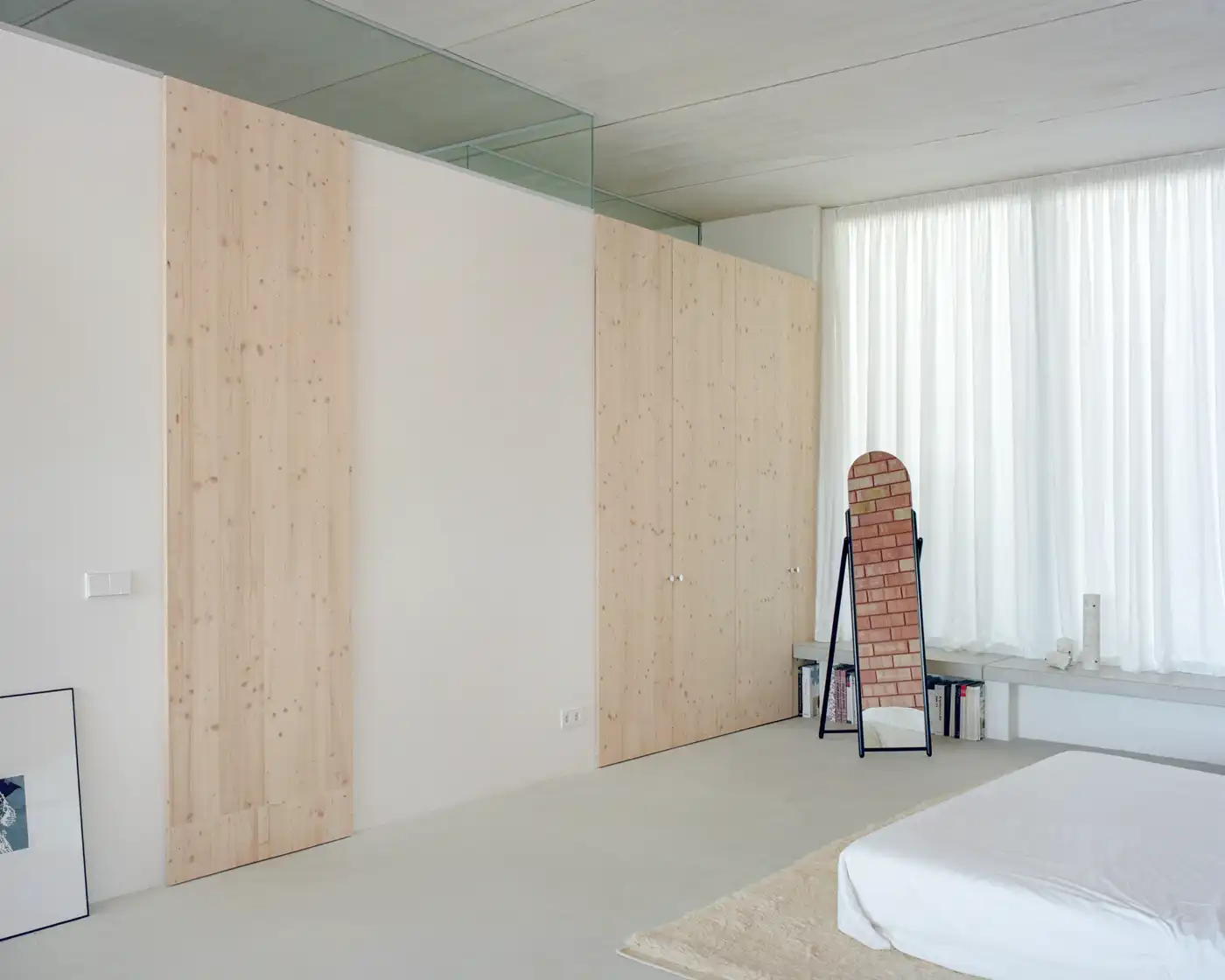 Casa Dosmurs by MESURA — Interior bedroom chamber defined by stacked pine plywood partition walls in natural light wood tone, creating modular spatial division.