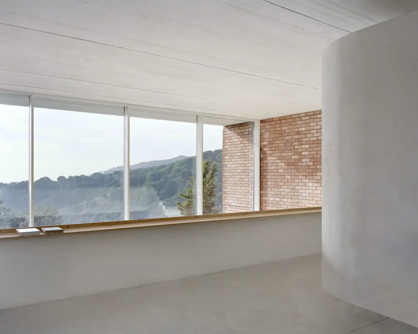 Casa Dosmurs by MESURA — Interior view of Casa Dosmurs showing a minimalist white-rendered space with polished concrete flooring.