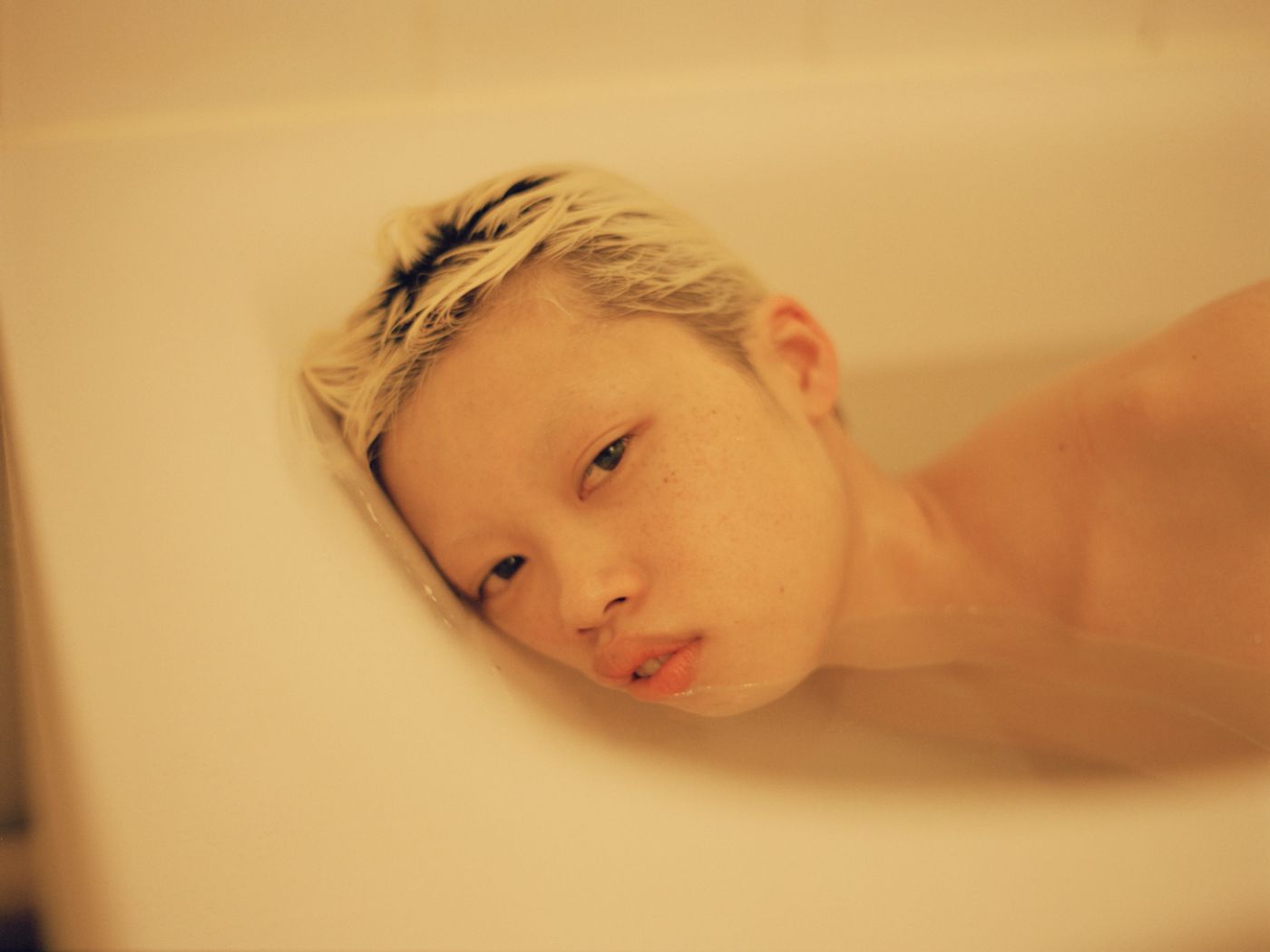 Visitors+ by Piczo — Close-up portrait of a young child in soft-focus repose against a neutral cream background.