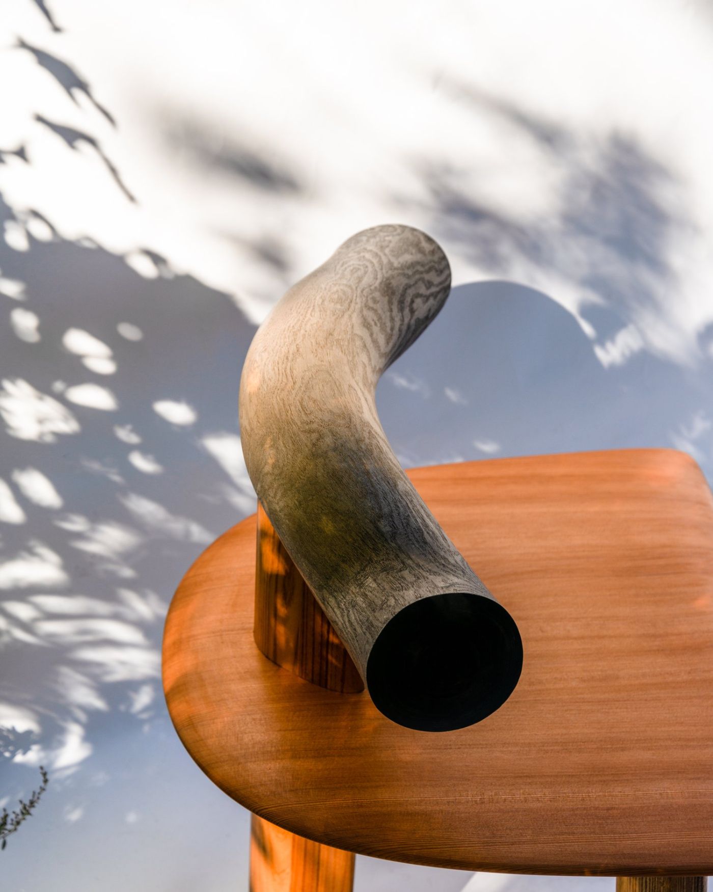 Selected 'Kanna' works by Studiovoll — A hand plane tool positioned vertically against a wooden panel, its curved wooden handle extending upward in a sculptural gesture.