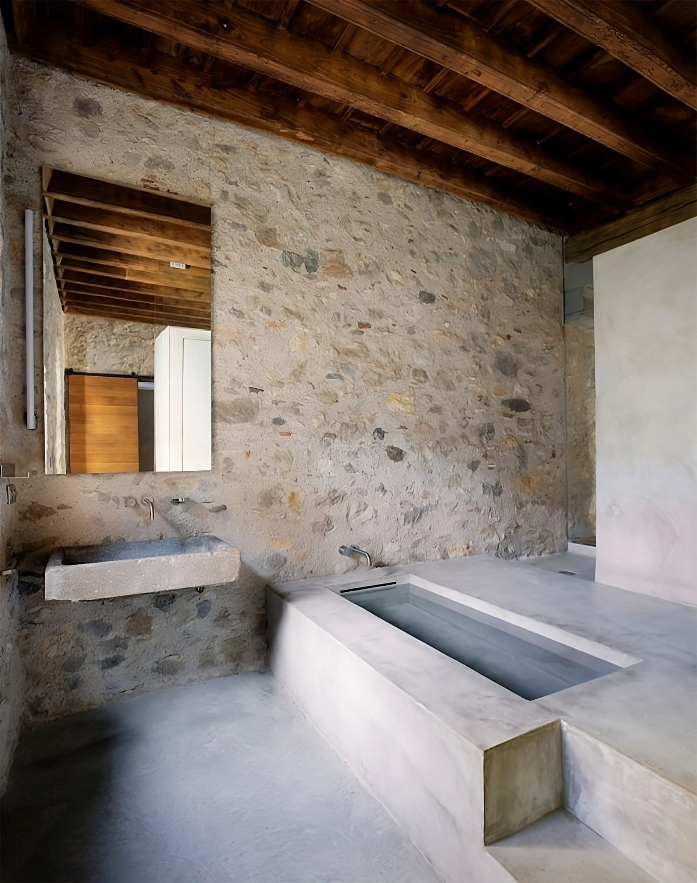Alemenys 5 by Anna Noguera — A monolithic concrete bathtub dominates this bathroom interior, its rectilinear form anchoring the space with sculptural presence.