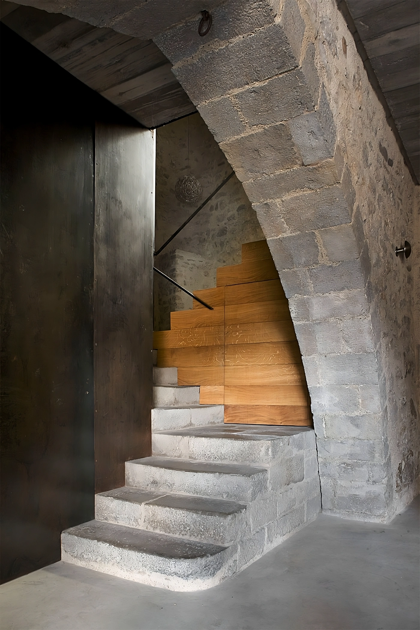 Alemenys 5 by Anna Noguera — Dual-flight staircase with oak treads ascending in opposing directions, separated by a dark timber partition wall.