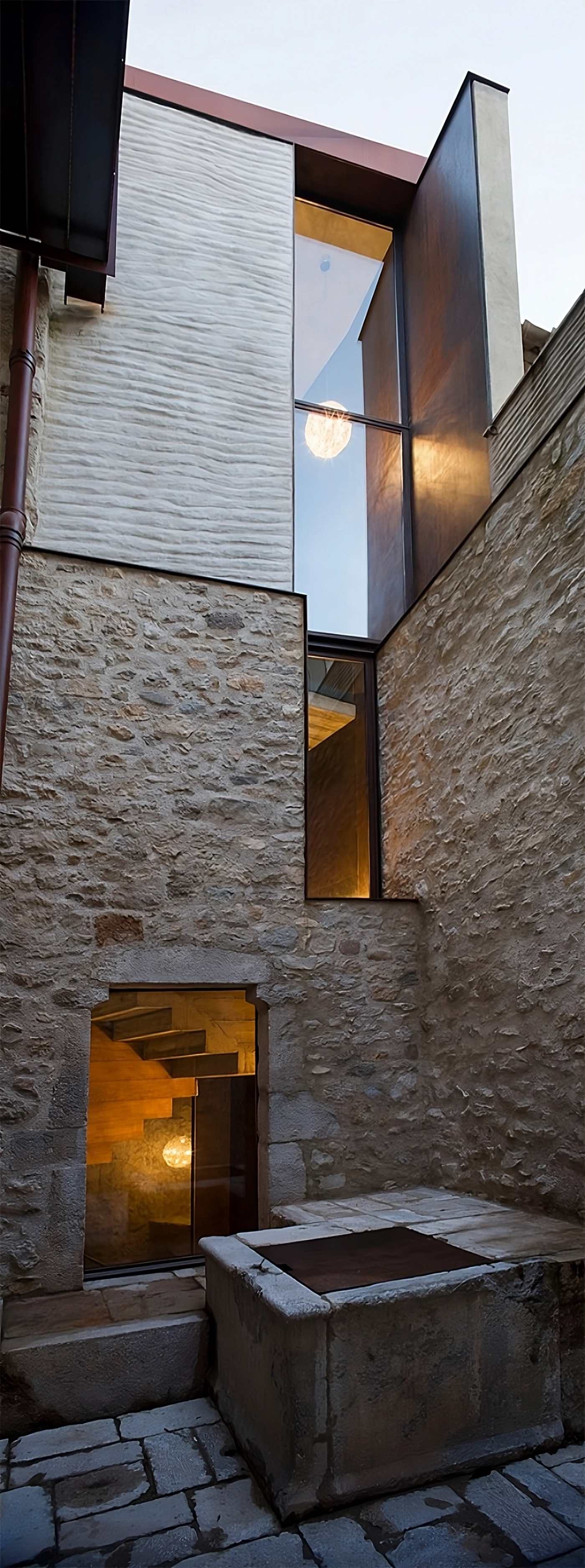 Alemenys 5 by Anna Noguera — A narrow courtyard passage framed by rough-hewn stone walls creates a compressed vertical void.