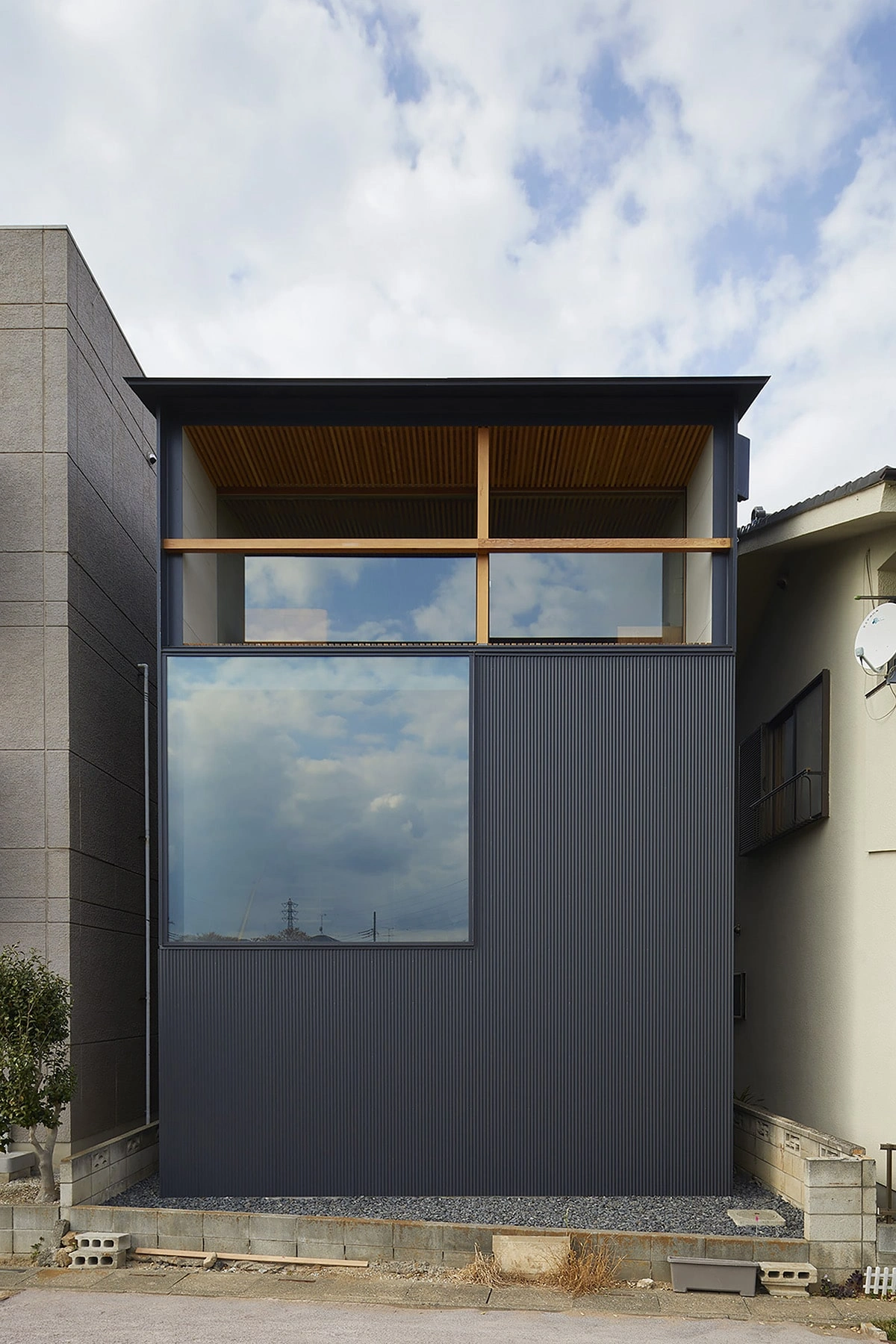 House in Gamo by Suppose Design Studio — A narrow residential addition wedged between existing structures demonstrates spatial efficiency through material stratification.