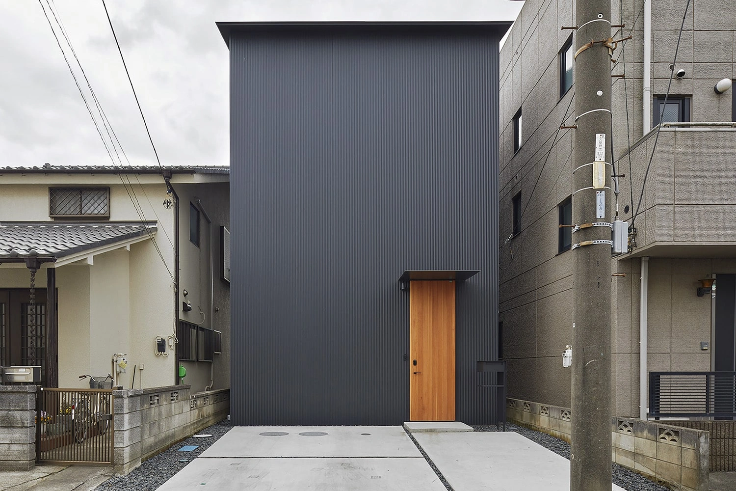 House in Gamo by Suppose Design Studio — Compressed between neighboring structures in Koshigaya, this narrow residential volume presents a monolithic dark facade of corrugated metal cladding that...
