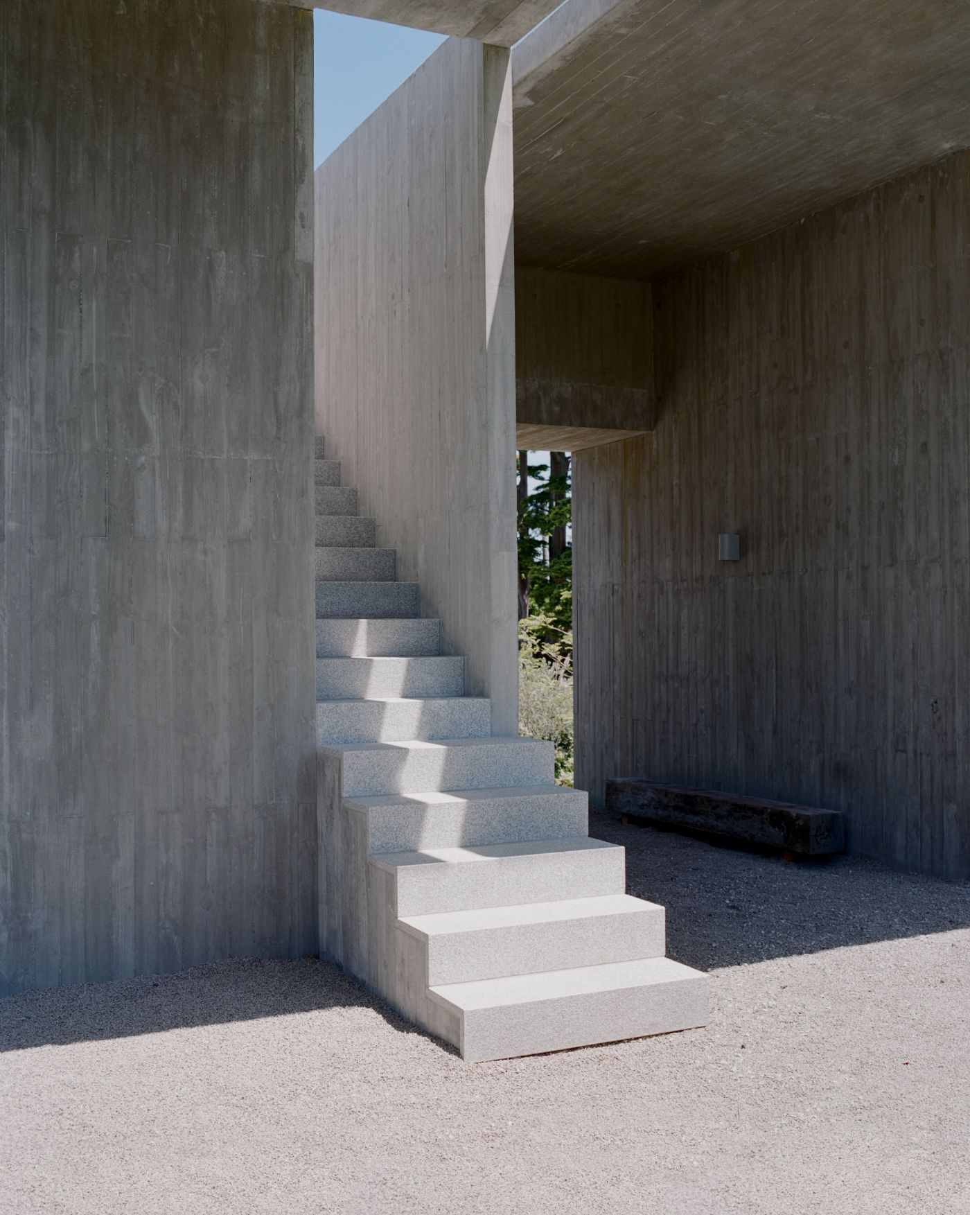Mori House by Aires Mateus + MAArchitects — A monolithic concrete staircase ascends through a narrow passage defined by board-formed concrete walls on either side.