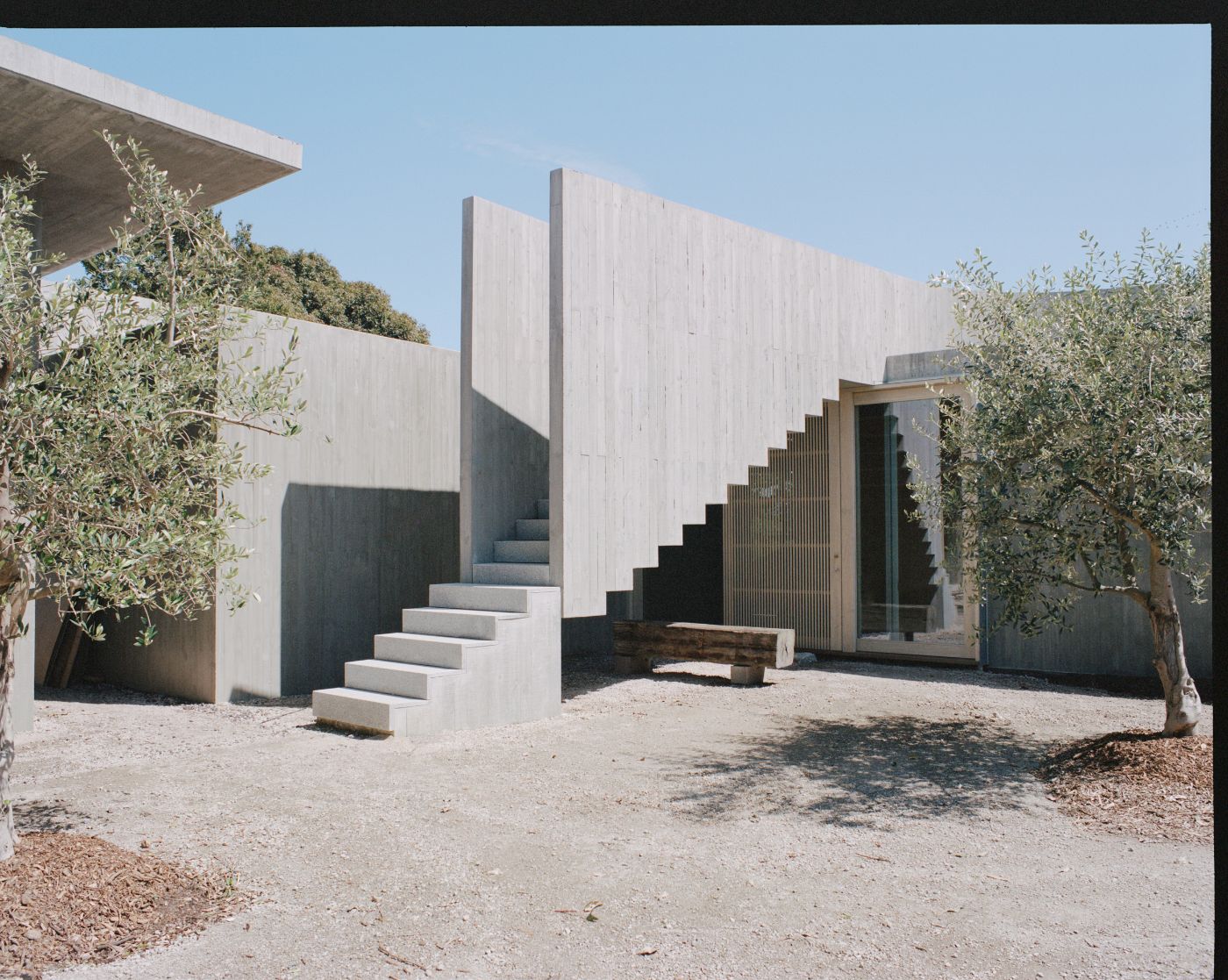 Mori House by Aires Mateus + MAArchitects — The courtyard approach to Mori House reveals a composition of monolithic concrete volumes punctuated by a dramatic cantilevered staircase.