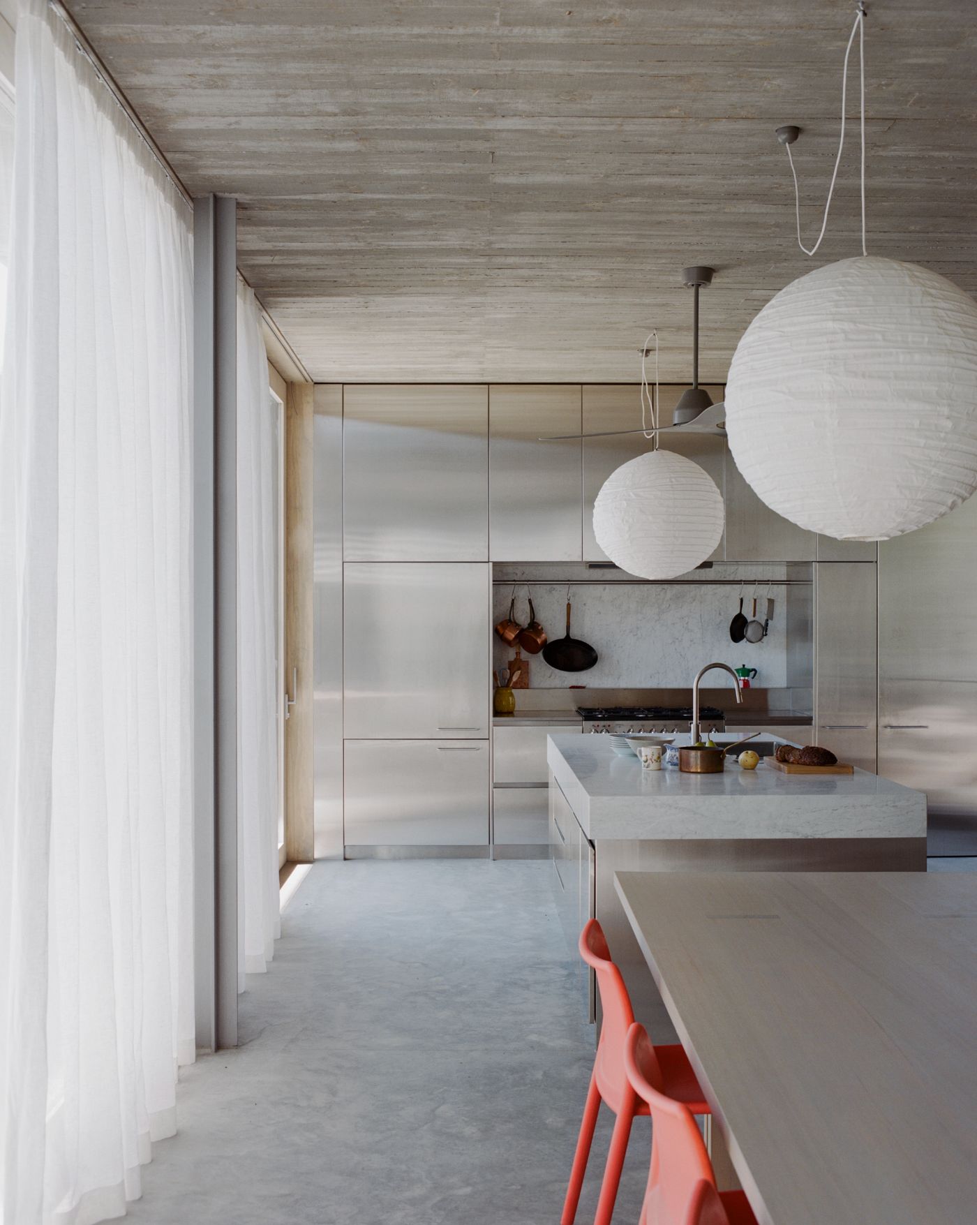 Mori House by Aires Mateus + MAArchitects — The kitchen interior demonstrates a restrained material palette anchored by polished concrete flooring and white-painted plasterboard walls.