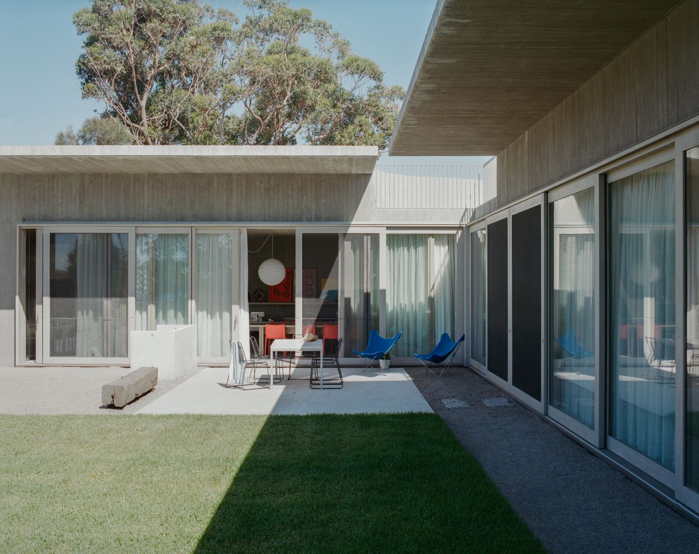 Mori House by Aires Mateus + MAArchitects — The rear courtyard elevation reveals the project's spatial complexity through continuous glazed walls with timber mullions framing interior volumes.