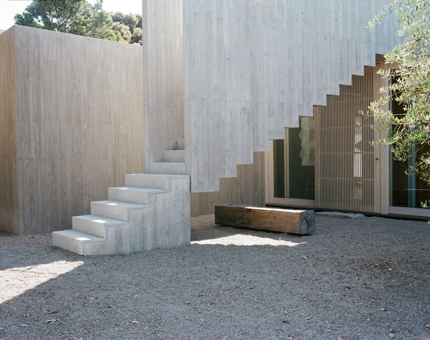 Mori House by Aires Mateus + MAArchitects — A monolithic concrete staircase dominates this courtyard passage, its geometric form cantilevered against whitewashed concrete walls.