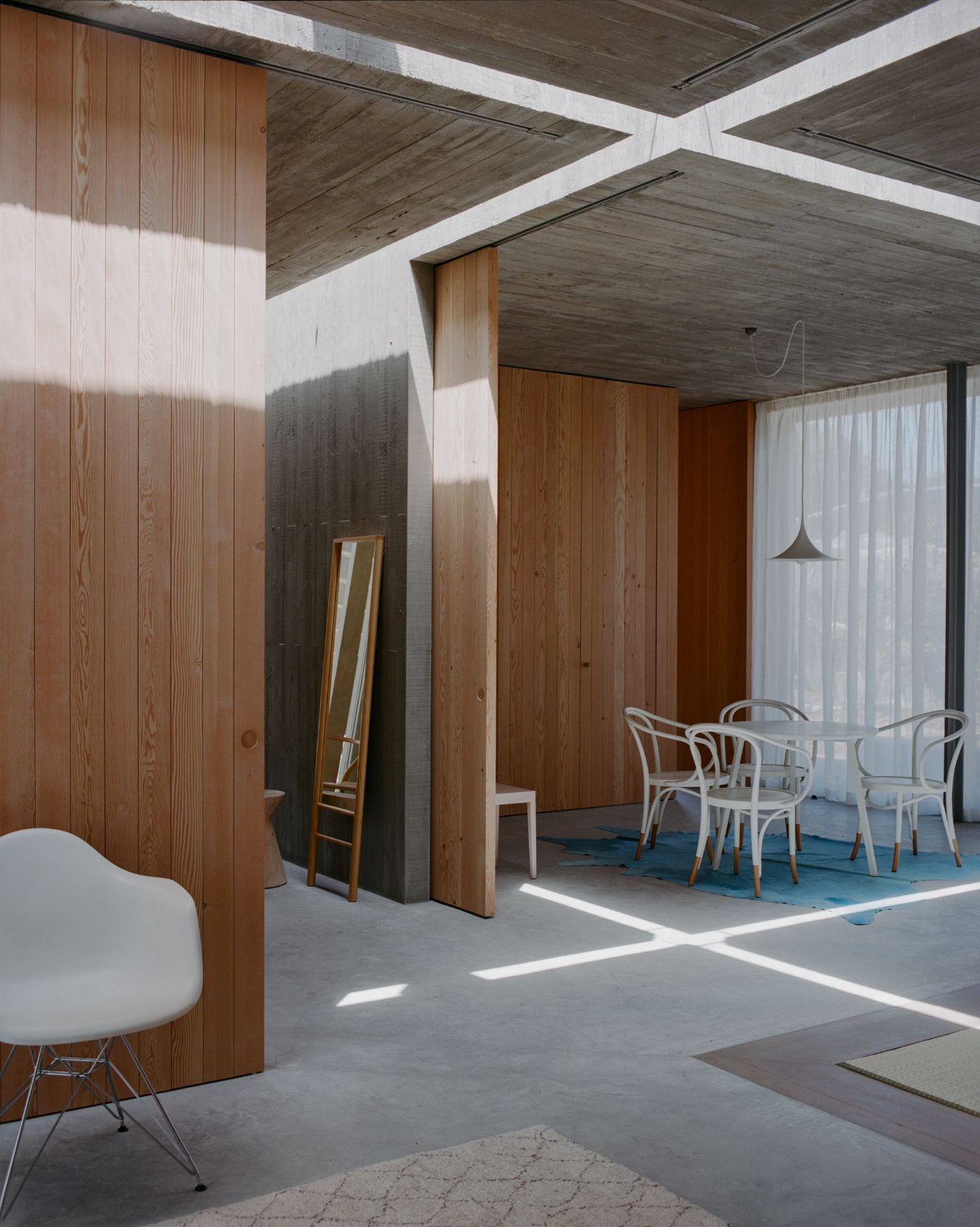 Mori House by Aires Mateus + MAArchitects — The interior of Mori House demonstrates spatial layering through timber-clad partition walls that fragment the open-plan living area.