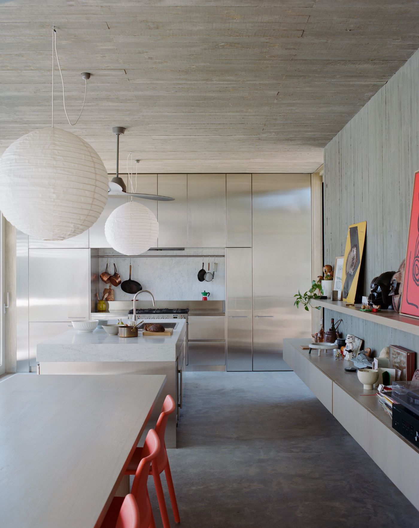 Mori House by Aires Mateus + MAArchitects — The kitchen interior demonstrates a restrained material palette anchored by polished concrete flooring and whitewashed vertical timber wall paneling.